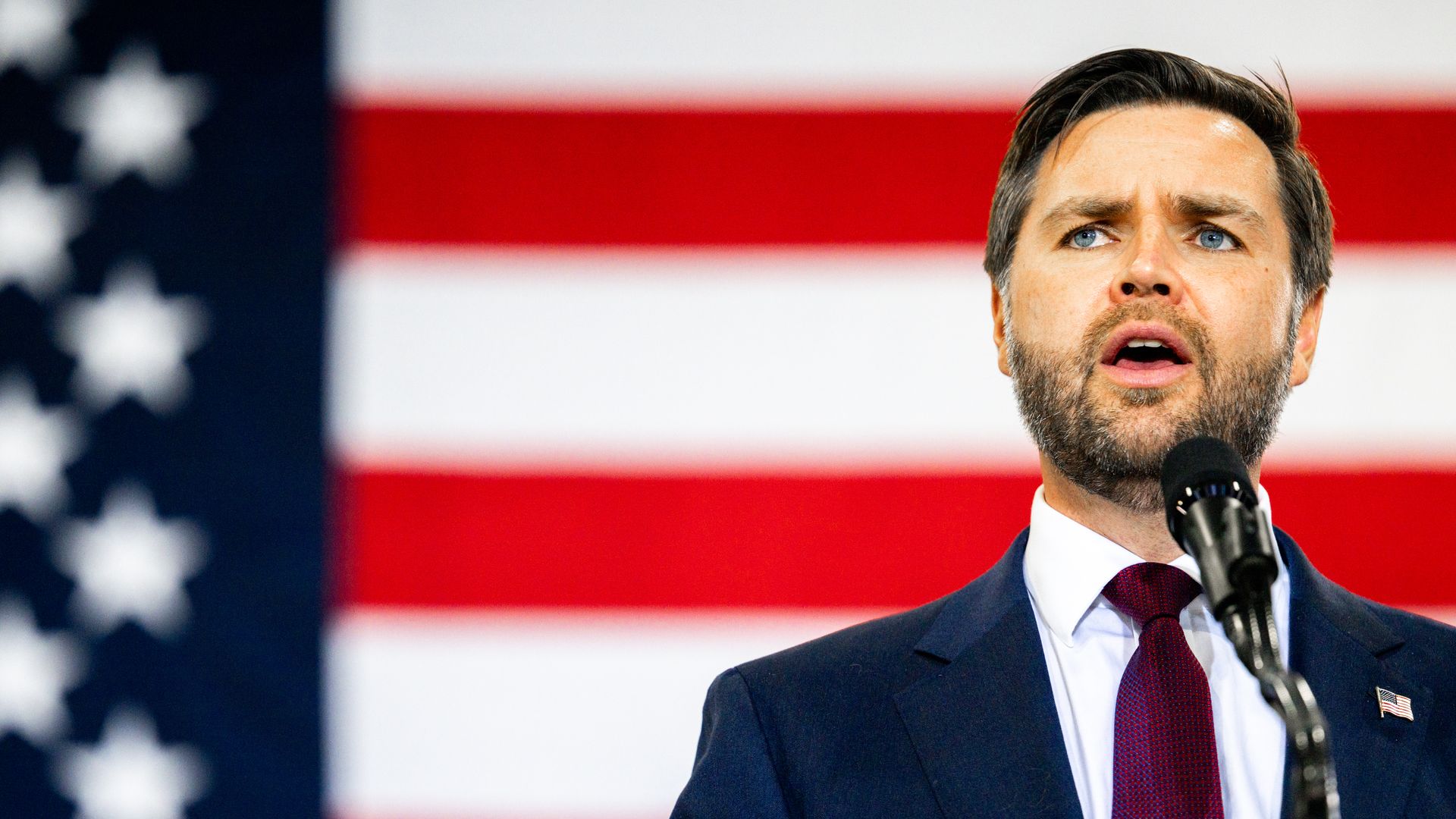 Ohio Sen. JD Vance speaks at a Trump campaign rally in front of an American flag.