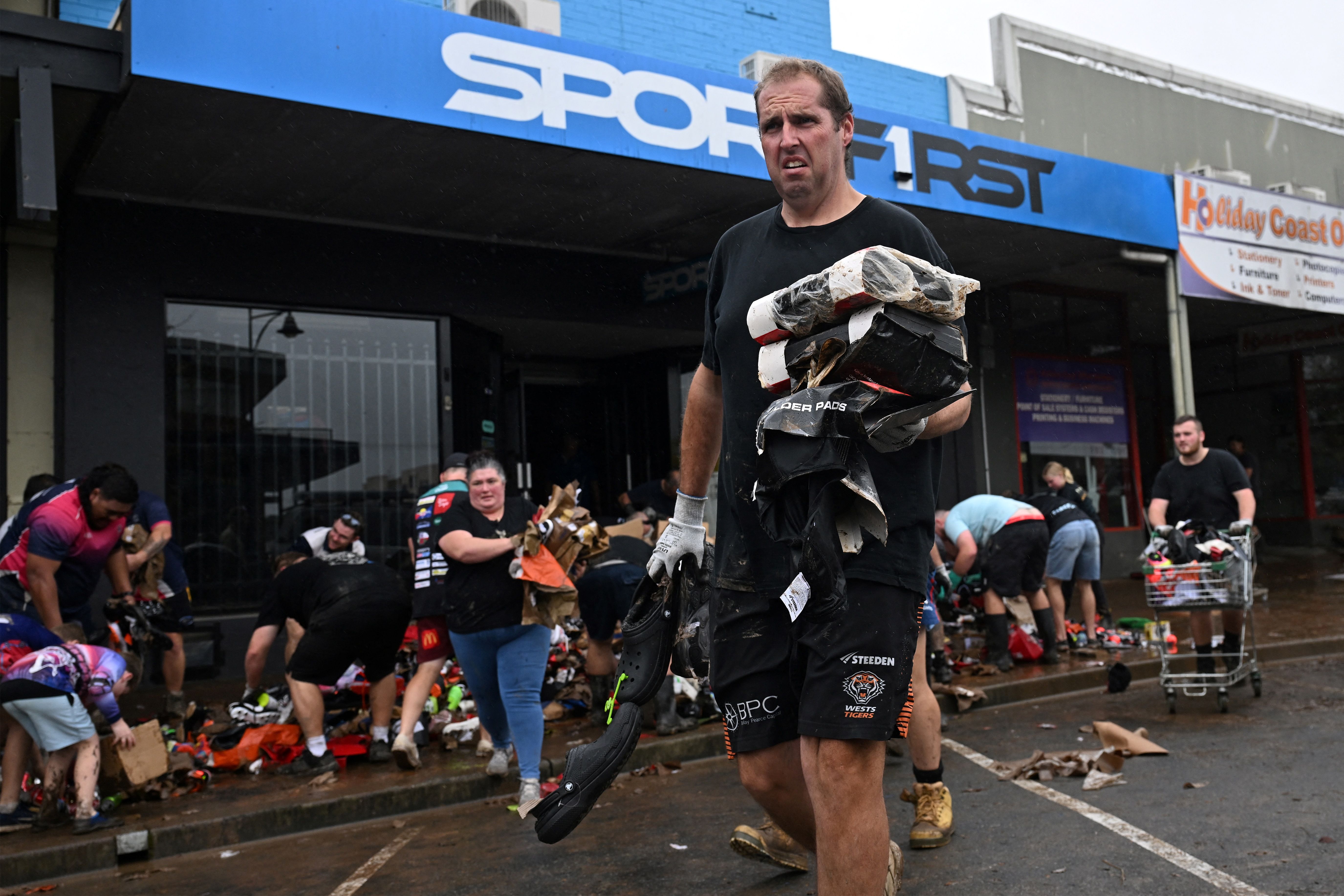 Volunteers help out locals to clear flood-damaged goods from their shops along the banks of the Manning River in Taree on May 23, 2025. 
