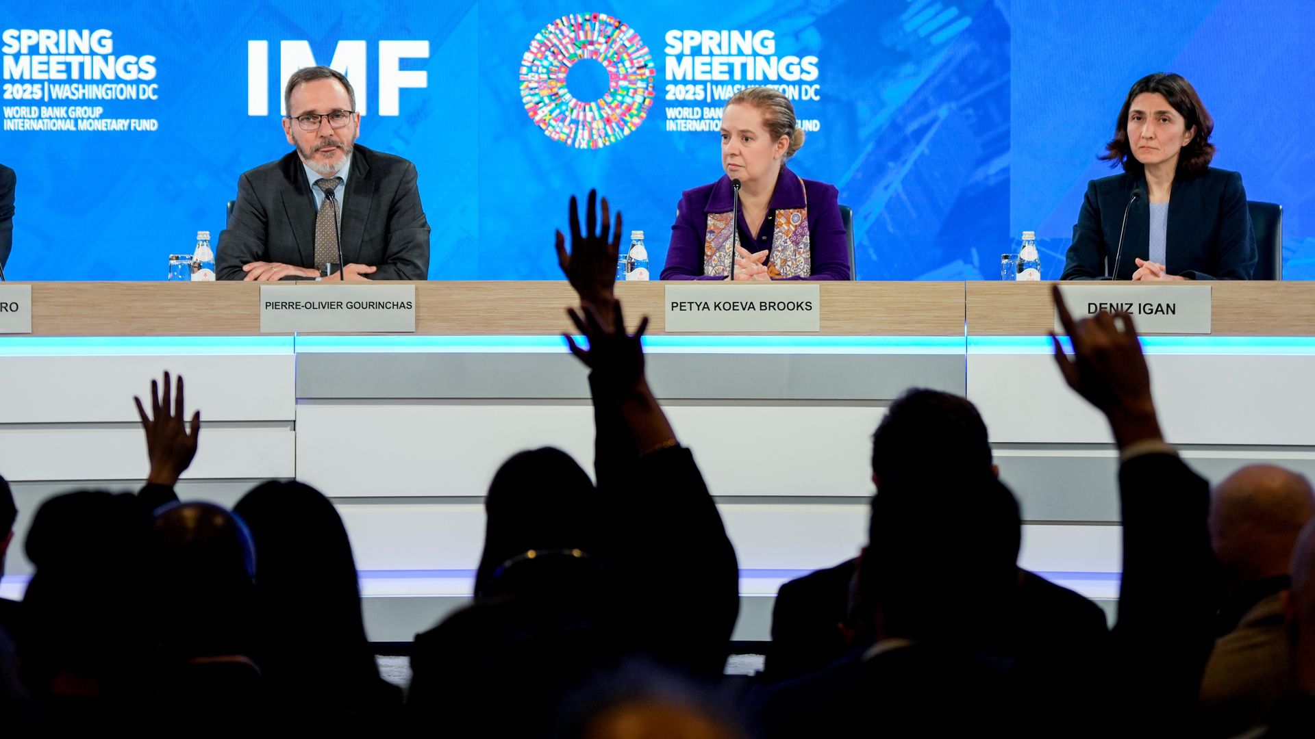 Reporters hands raised as IMF economists brief on the global economic outlook
