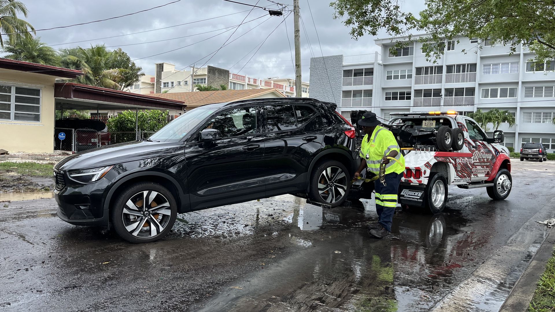 A tow truck driver tows away a car stranded in flood waters.