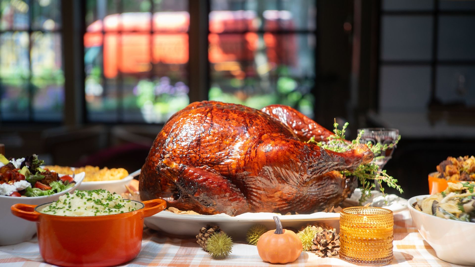 Turkey on a platter on a table, surrounding by bowls of side dishes