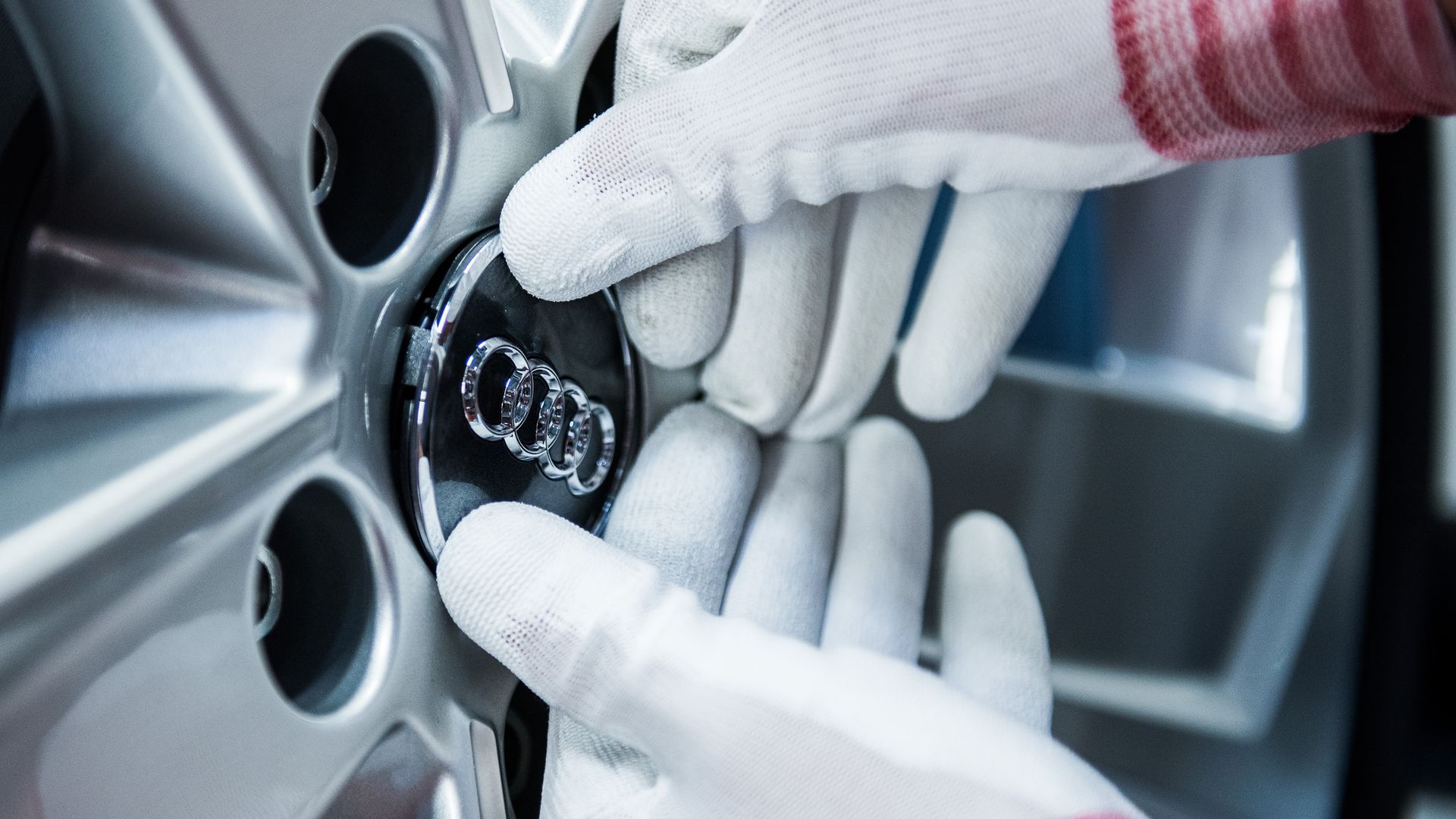 A person with gloves applying an Audi logo to a wheel hub.