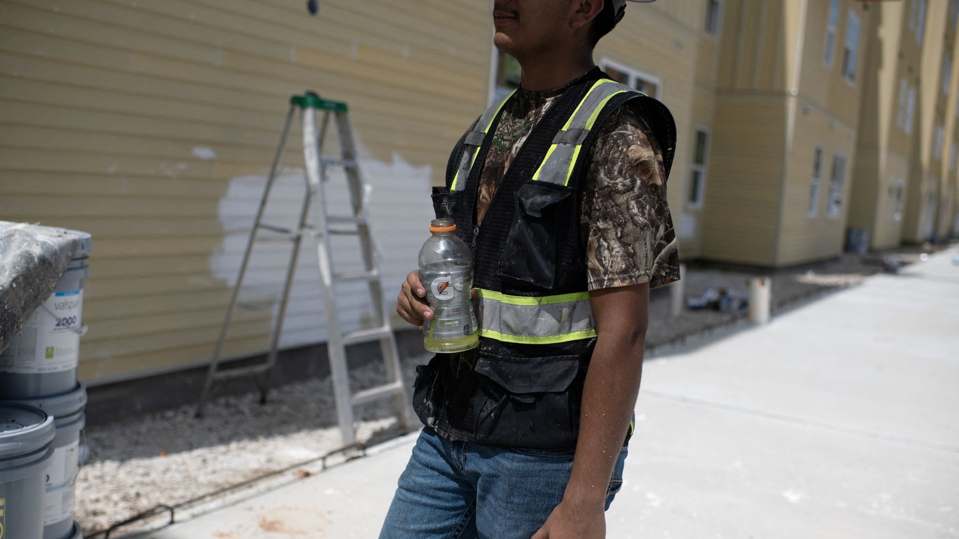 A construction worker holds a half-full gatorade 