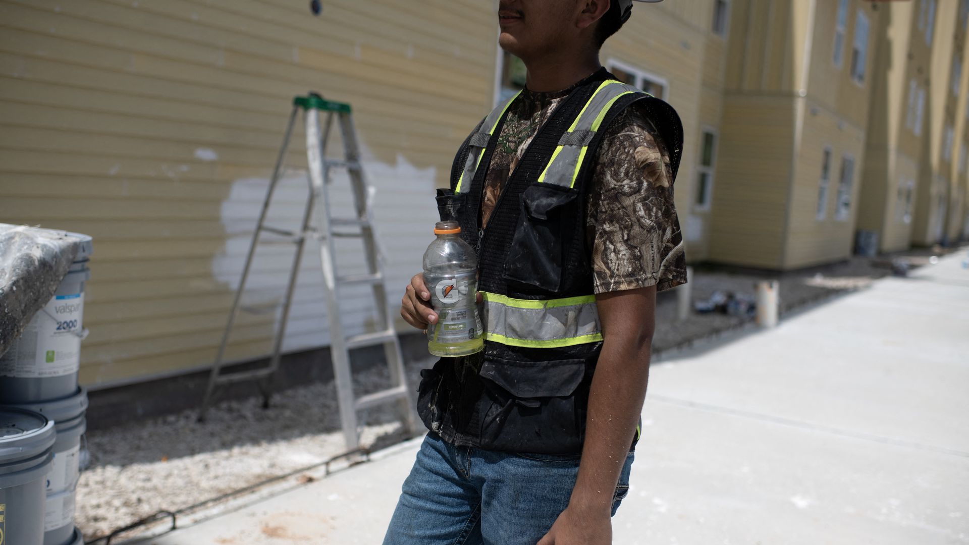 A construction worker holds a half-full gatorade