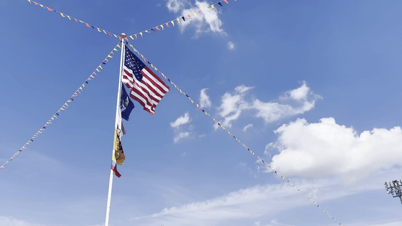 A moving image of the flag pole at the center of Jazz Fest. The flags wave in the breeze.