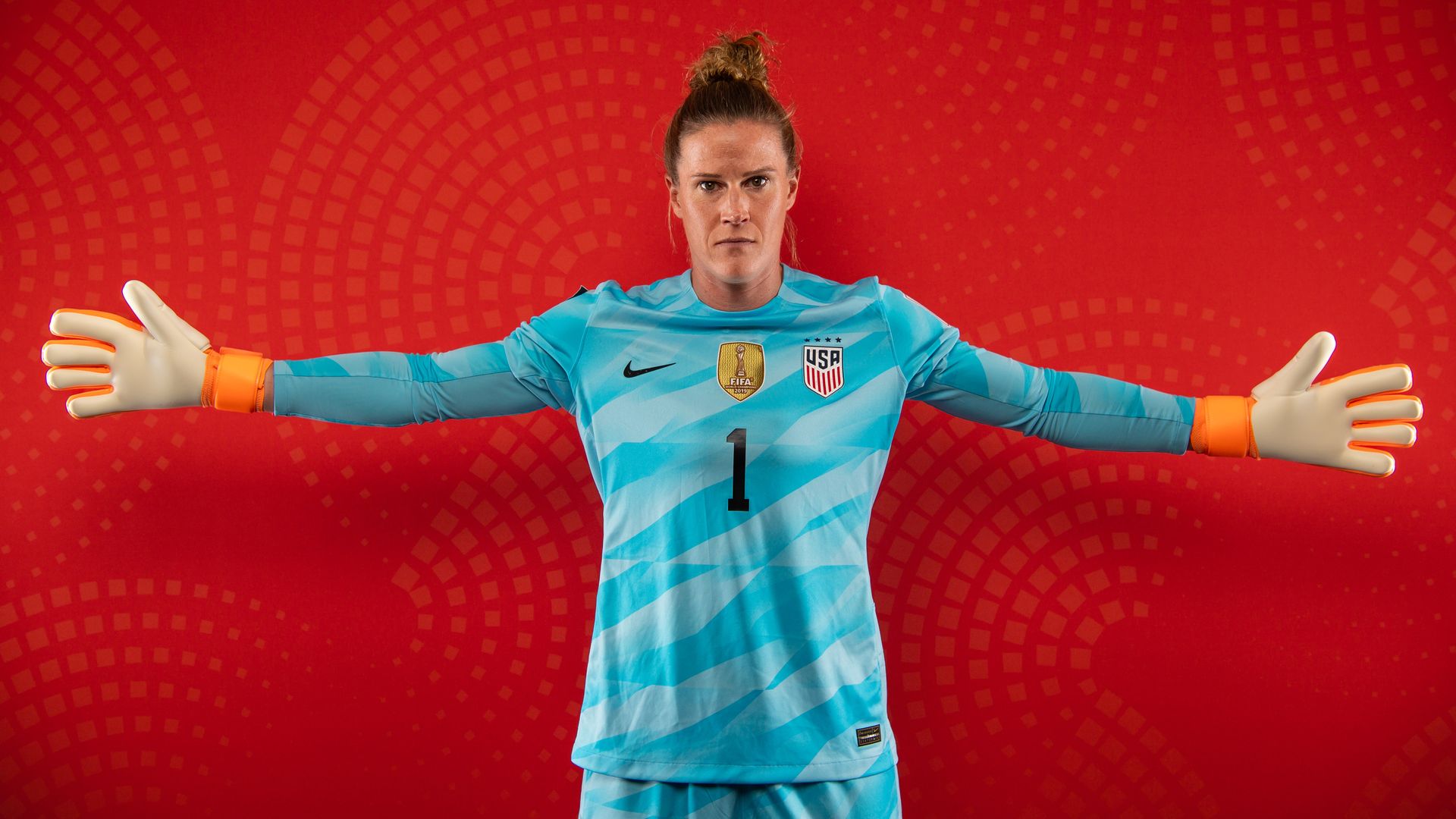 Goalie in blue uniform with arms outstretched in front of a red background.