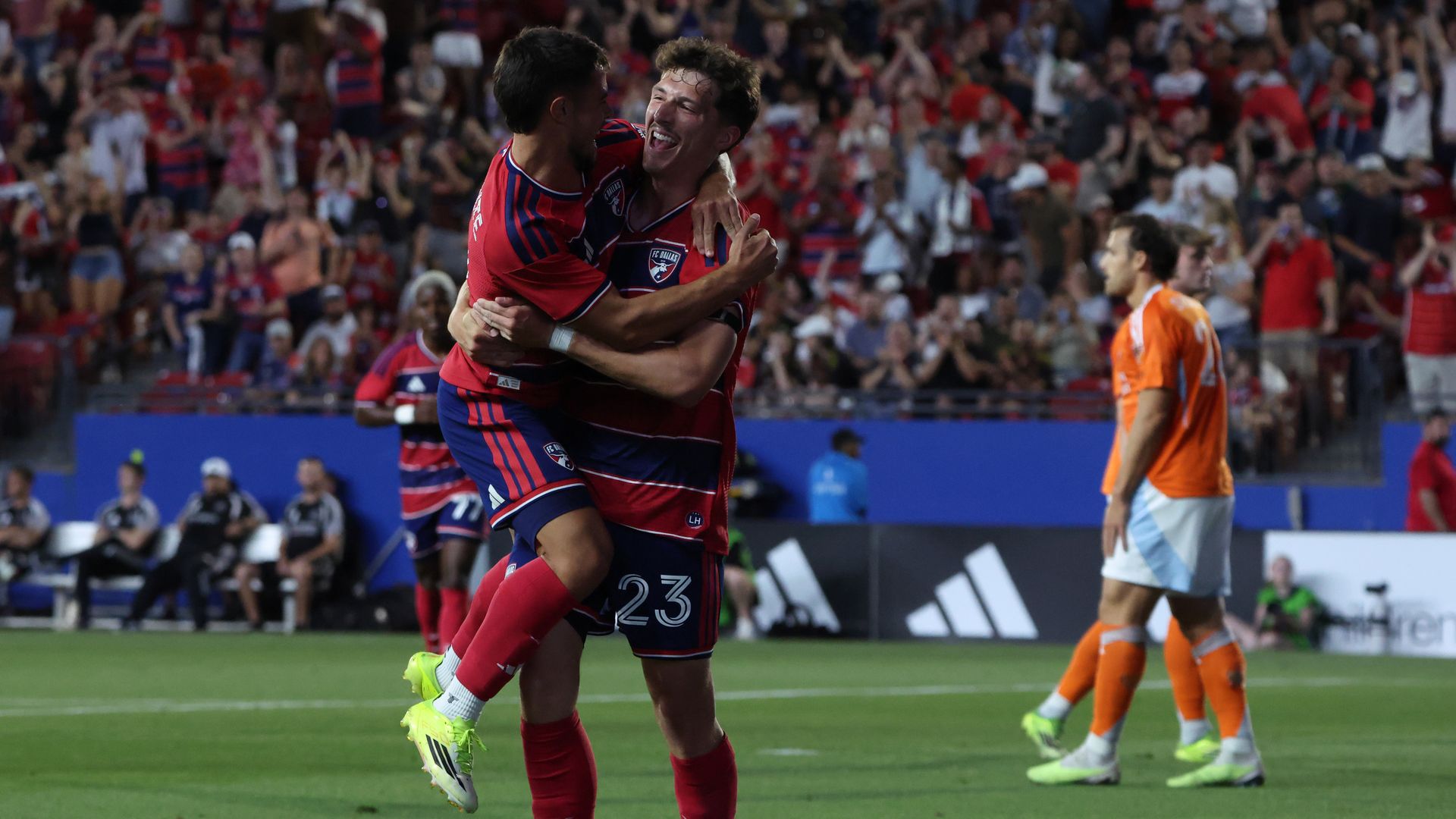 Two players hug each other on a soccer field