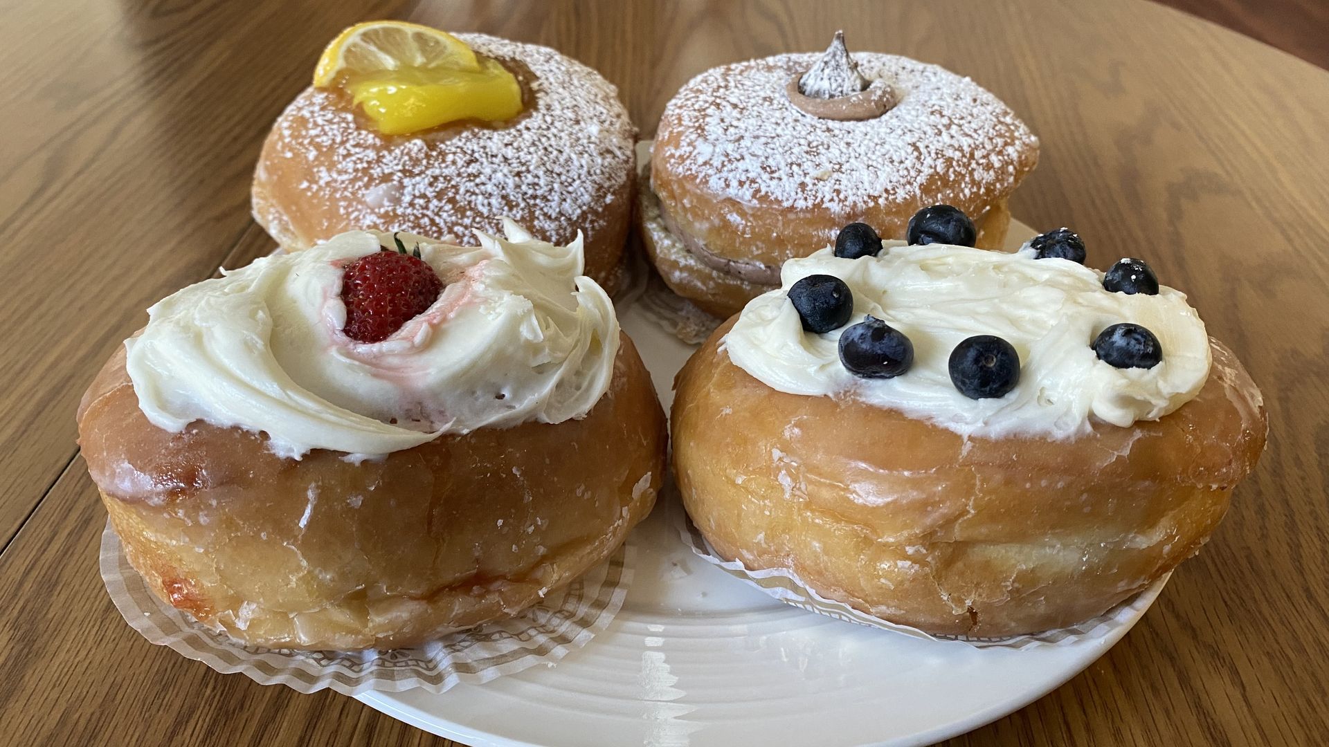 Four pączki on a plate, with fruit topping on them