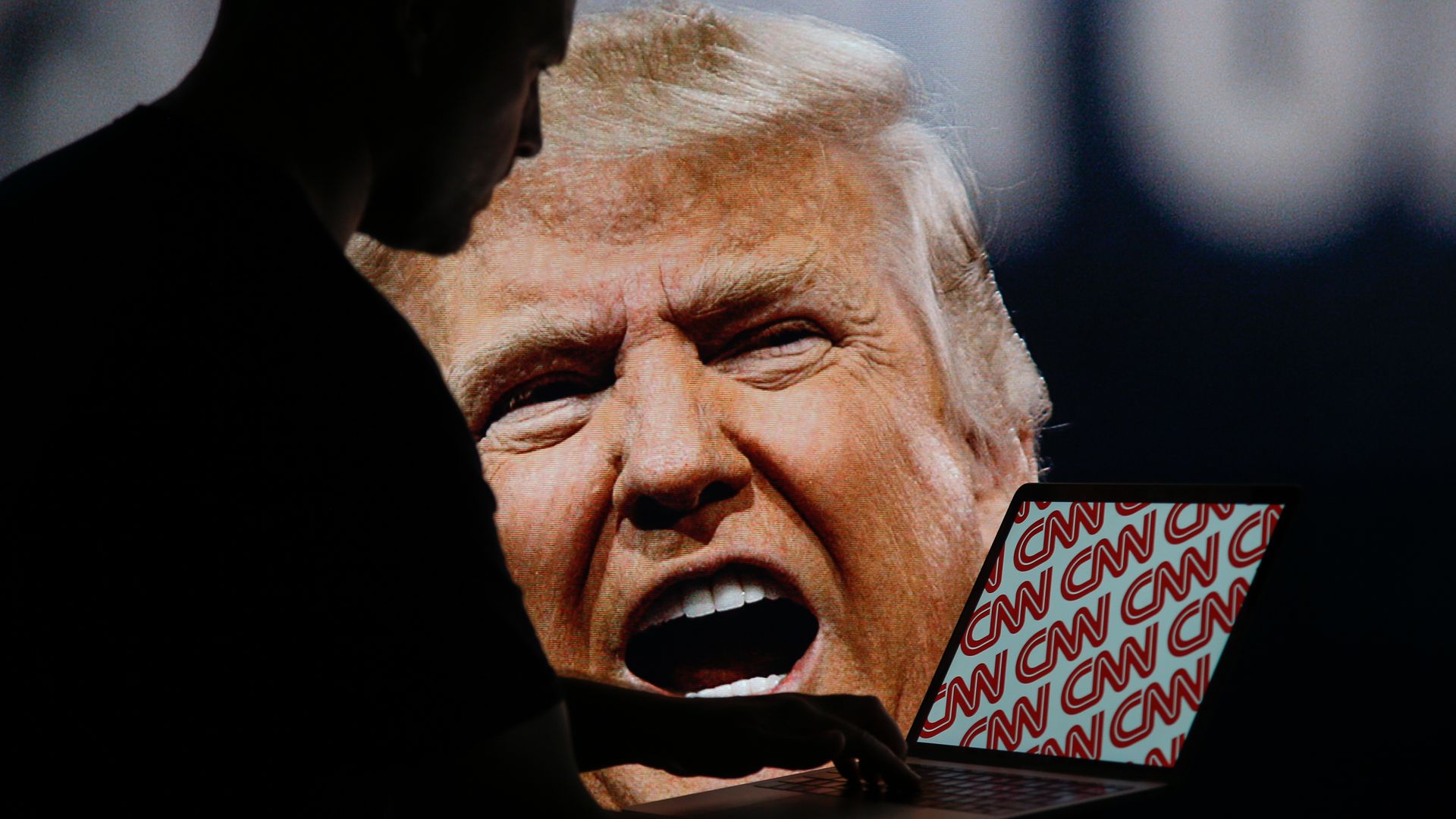 Trump on a big screen behind a laptop with the CNN logo