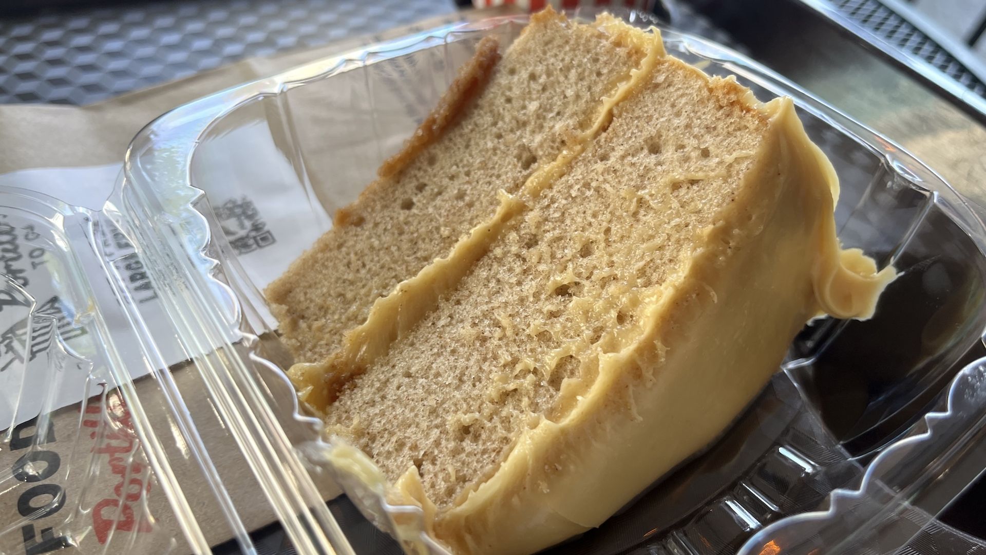 Yellow cake with caramel color frosting in a plastic clamshell. 
