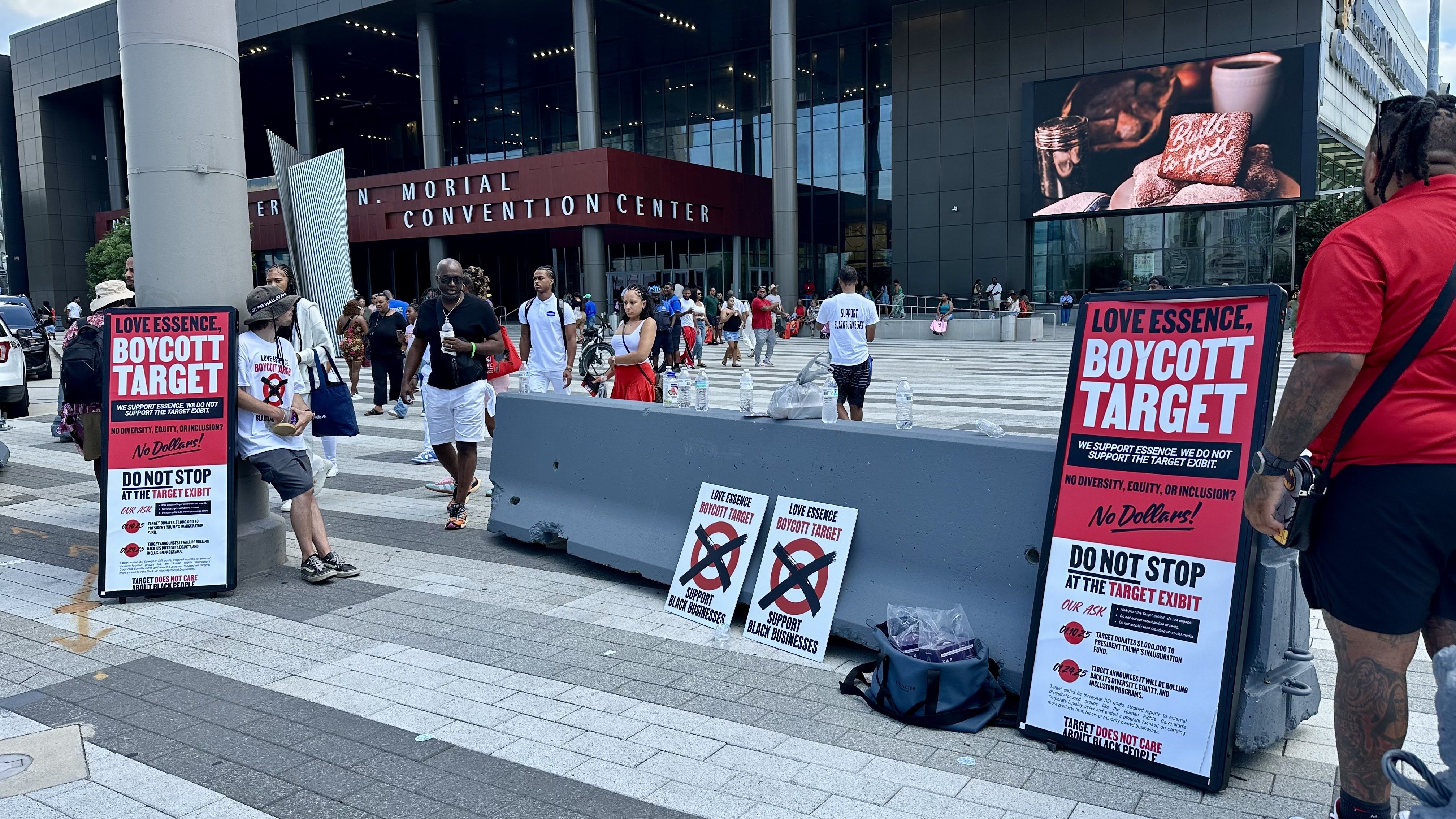 Protesters outside Ernest N. Morial Convention Center hold red and white signs reading "Love Essence, Boycott Target" with messages supporting black businesses and condemning Target's inclusion efforts.