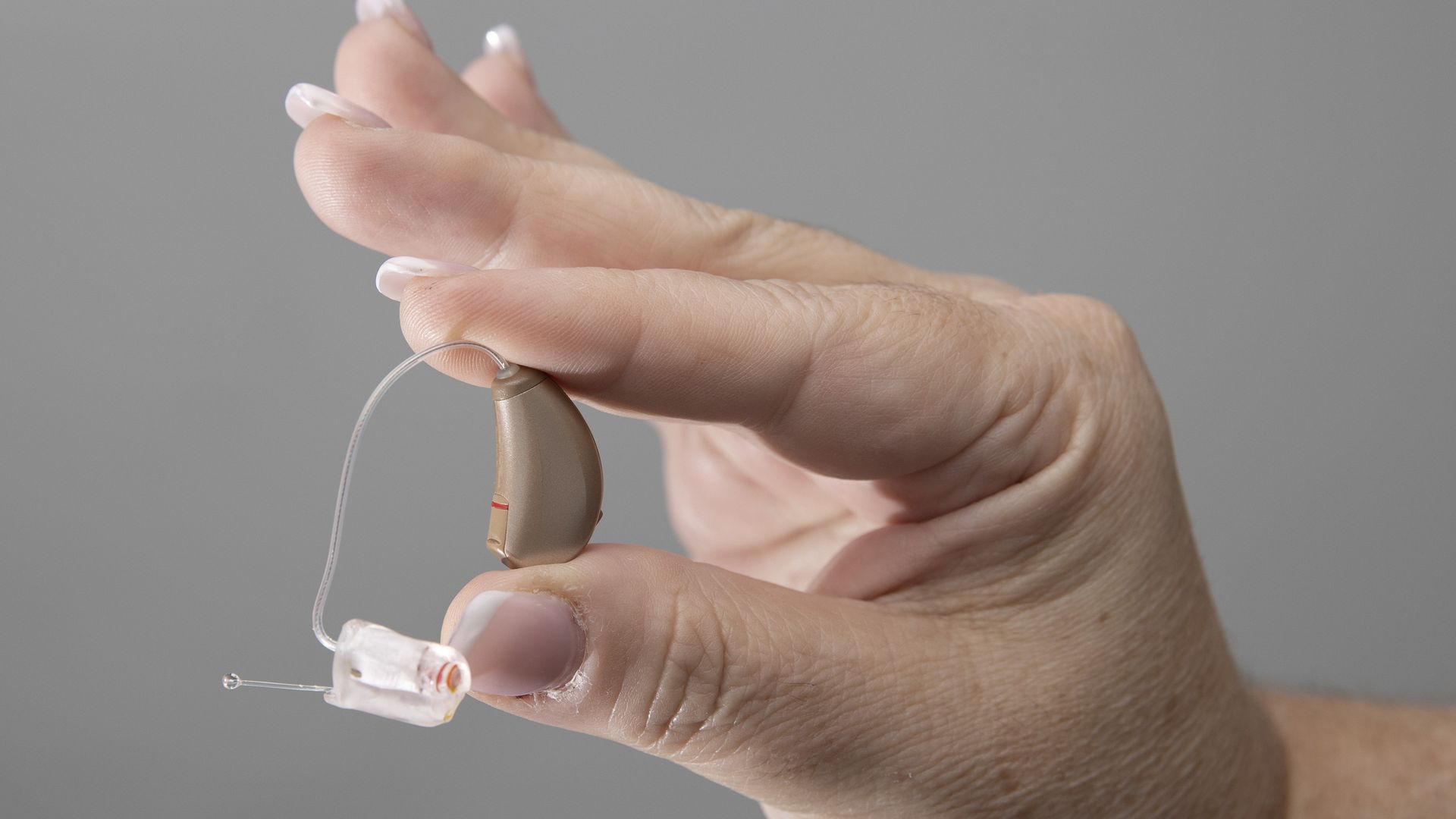 A hand holds a hearing aid