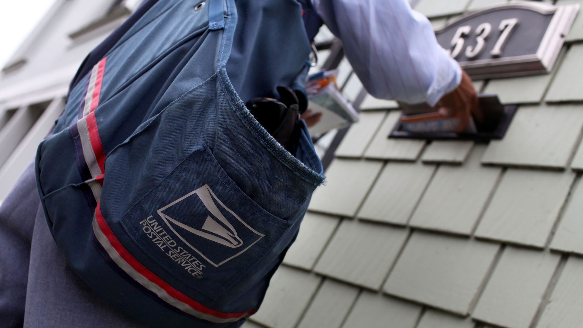 Photo of a postal service worker delivering mail