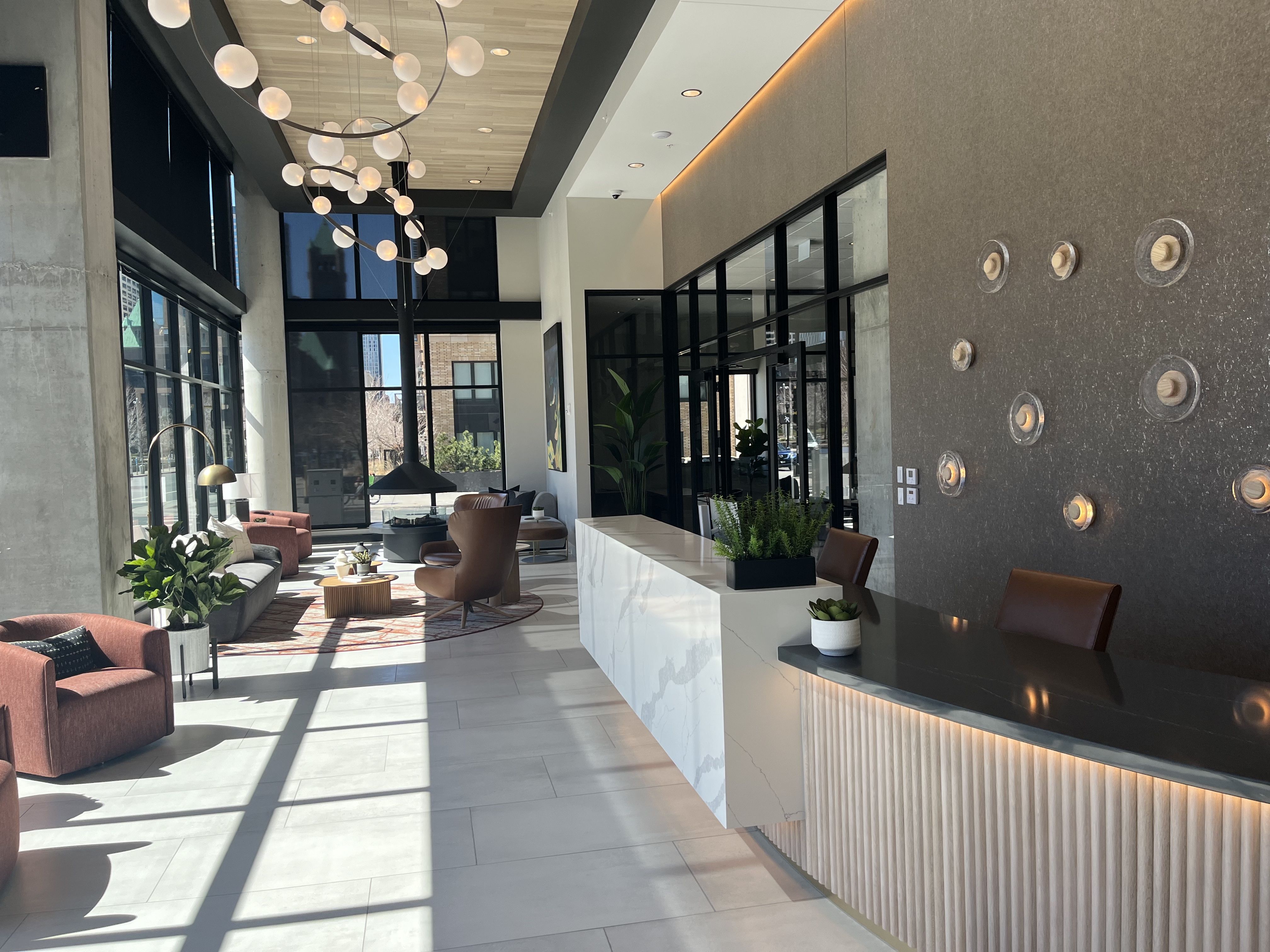 A lobby with hanging lights, couches and a front desk 