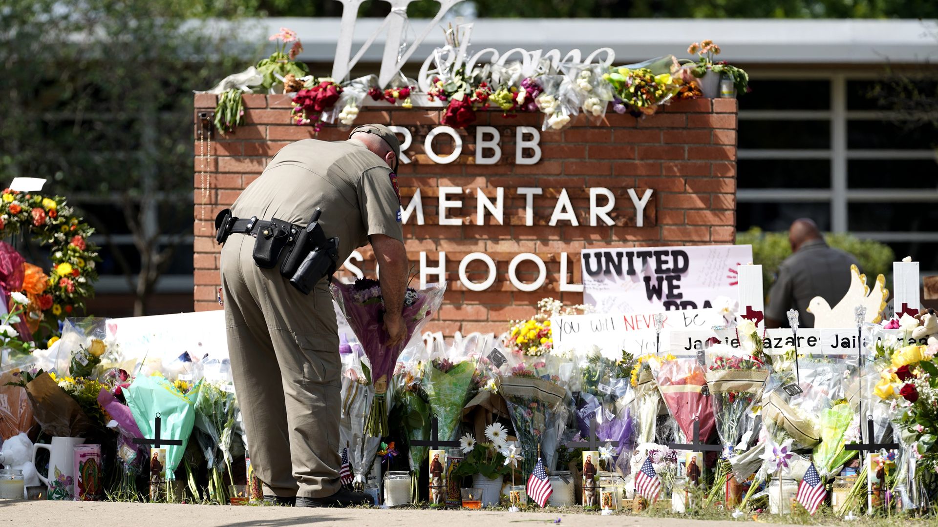 A police officer lays flowers outside Robb Elementary School in the town of Uvalde, Texas, the United States, May 27, 2022. At least 19 children and two adults were killed in a shooting at Robb Elementary School in the town of Uvalde, Texas, on Tuesday. (Photo by Wu Xiaoling/Xinhua via Getty Images)