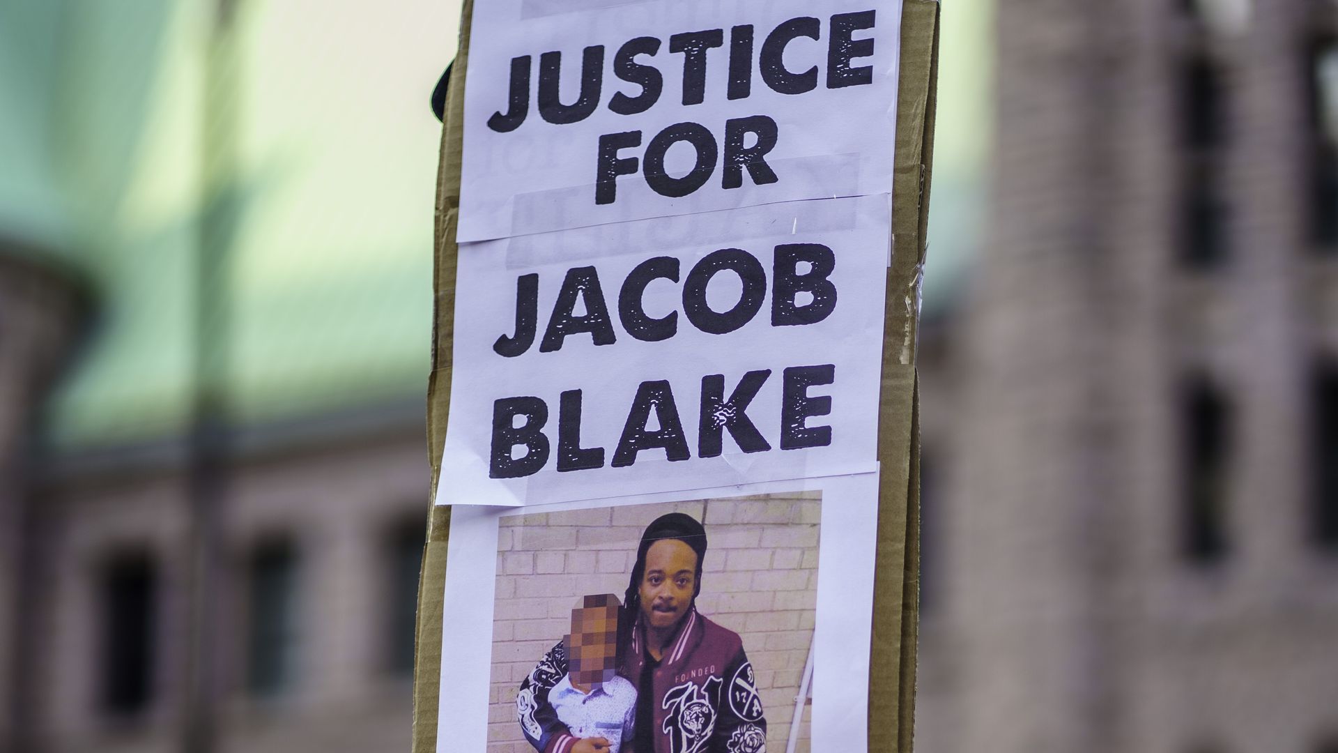 A Protester holds sign of "Jacob Blake" picture outside Hennepin County Government Plaza during a demonstration against police brutality and racism