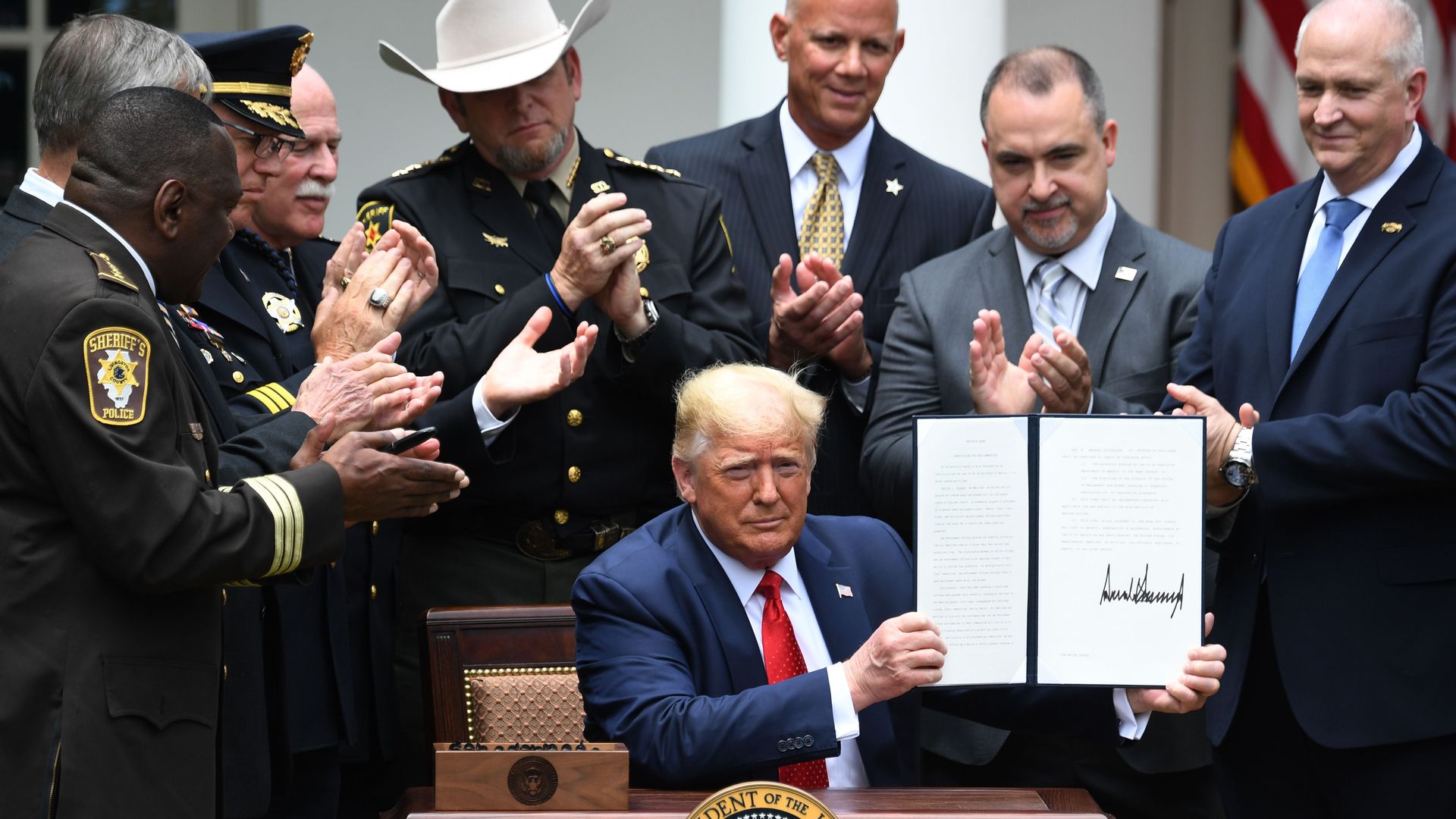 US President Donald Trump shows his signature on an Executive Order on Safe Policing for Safe Communities, in the Rose Garden of the White House