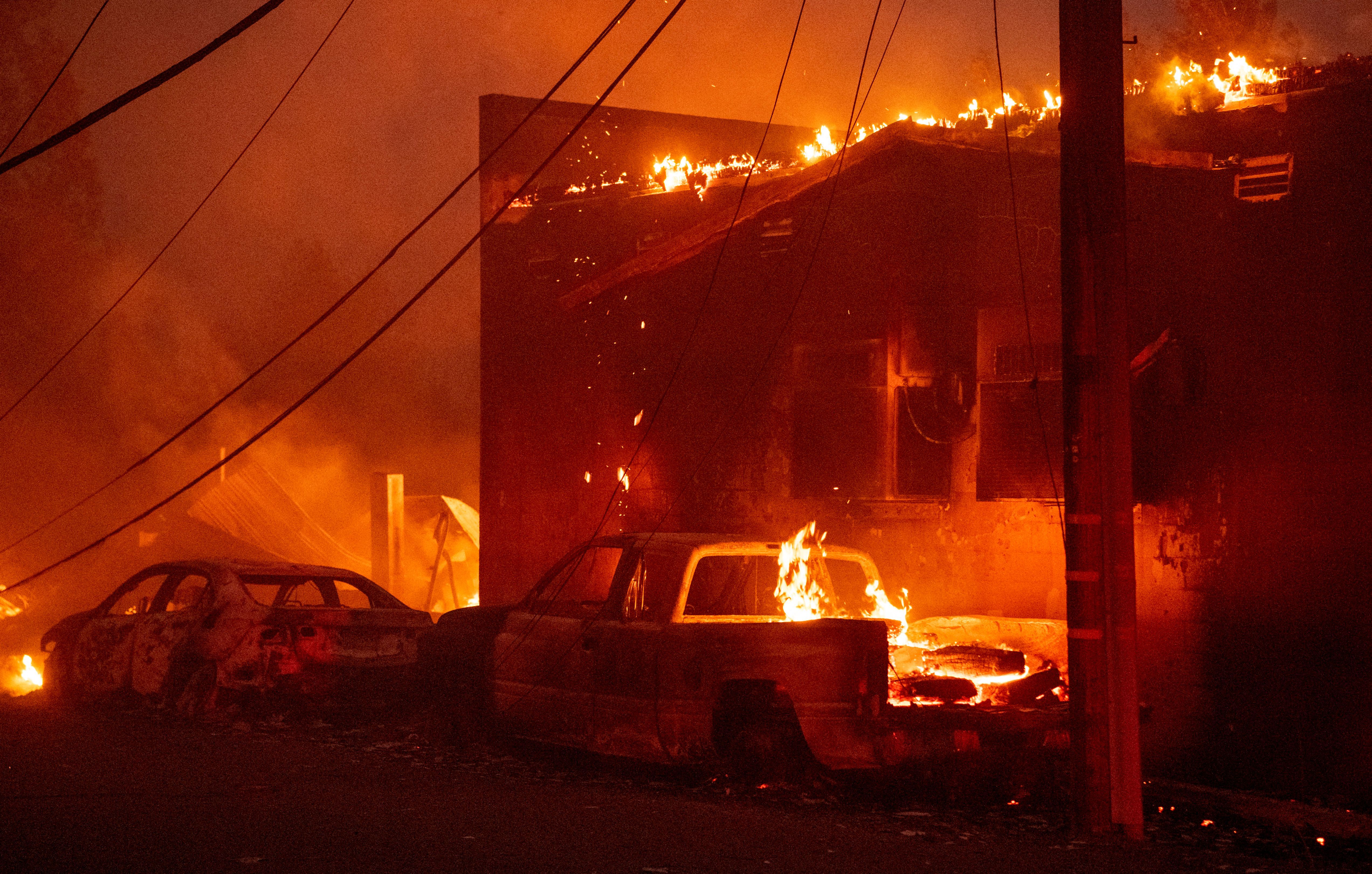 Vehicles and a building burn during the Dixie fire in downtown Greenville, California on August 4, 2021.