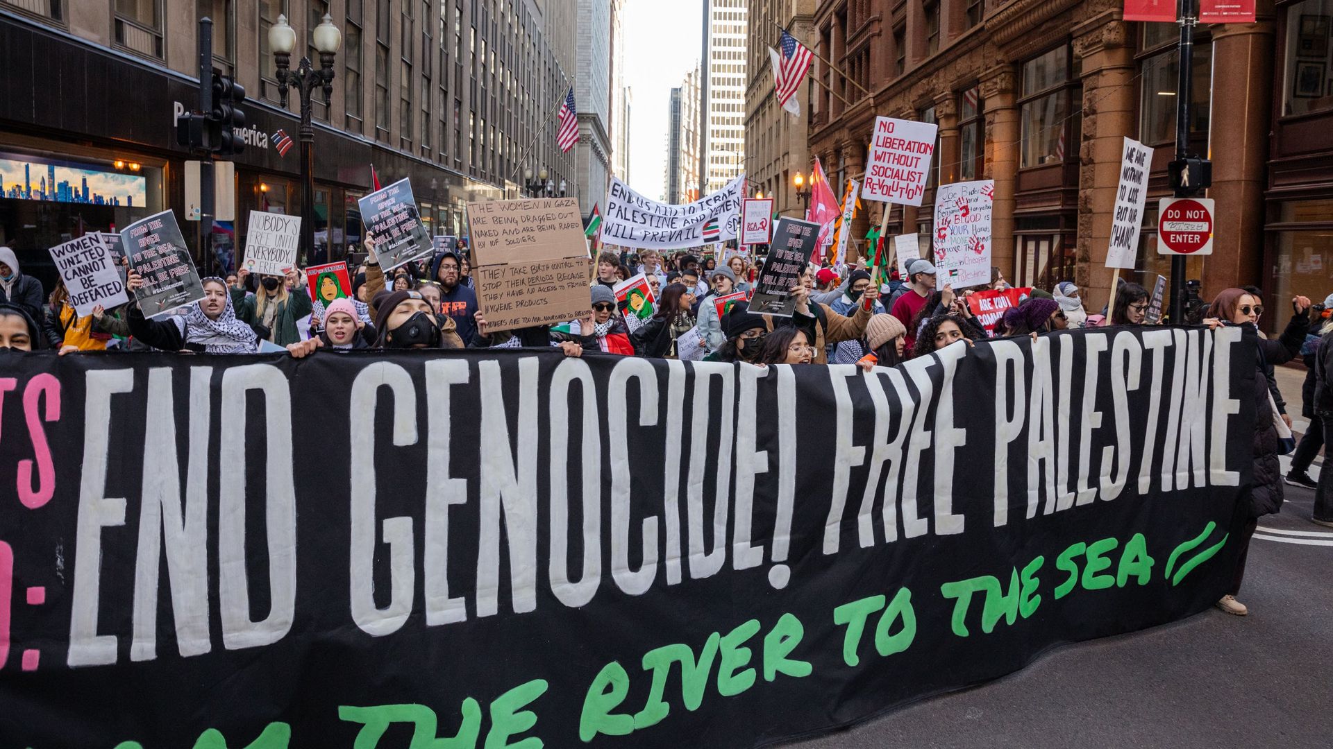 Demonstrators holding signs and holding a banner that reads End Genocide Free Palestine.