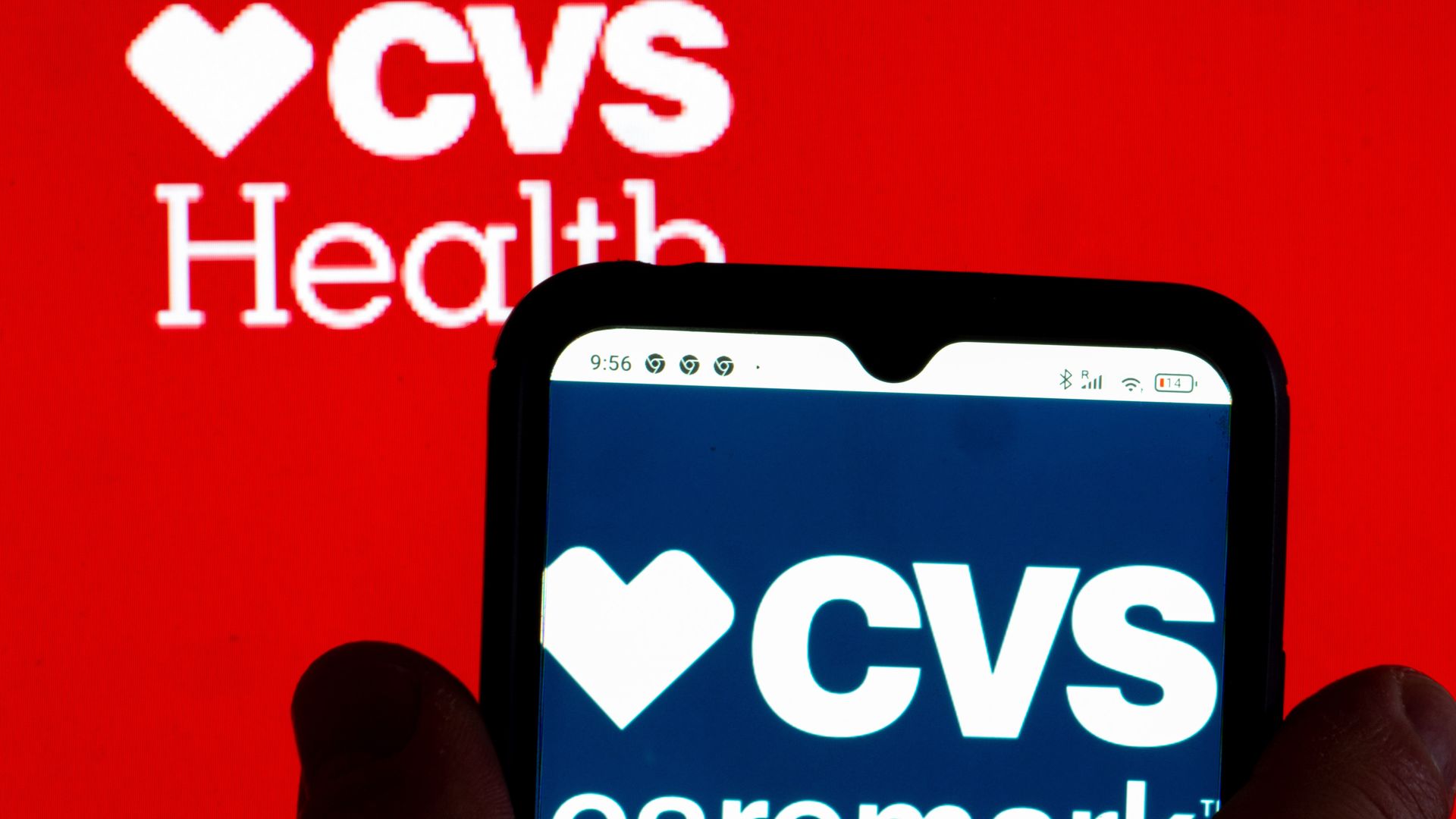 In this photo illustration, the CVS Caremark logo is displayed on a smartphone screen with a CVS Health Corporation logo in the background.