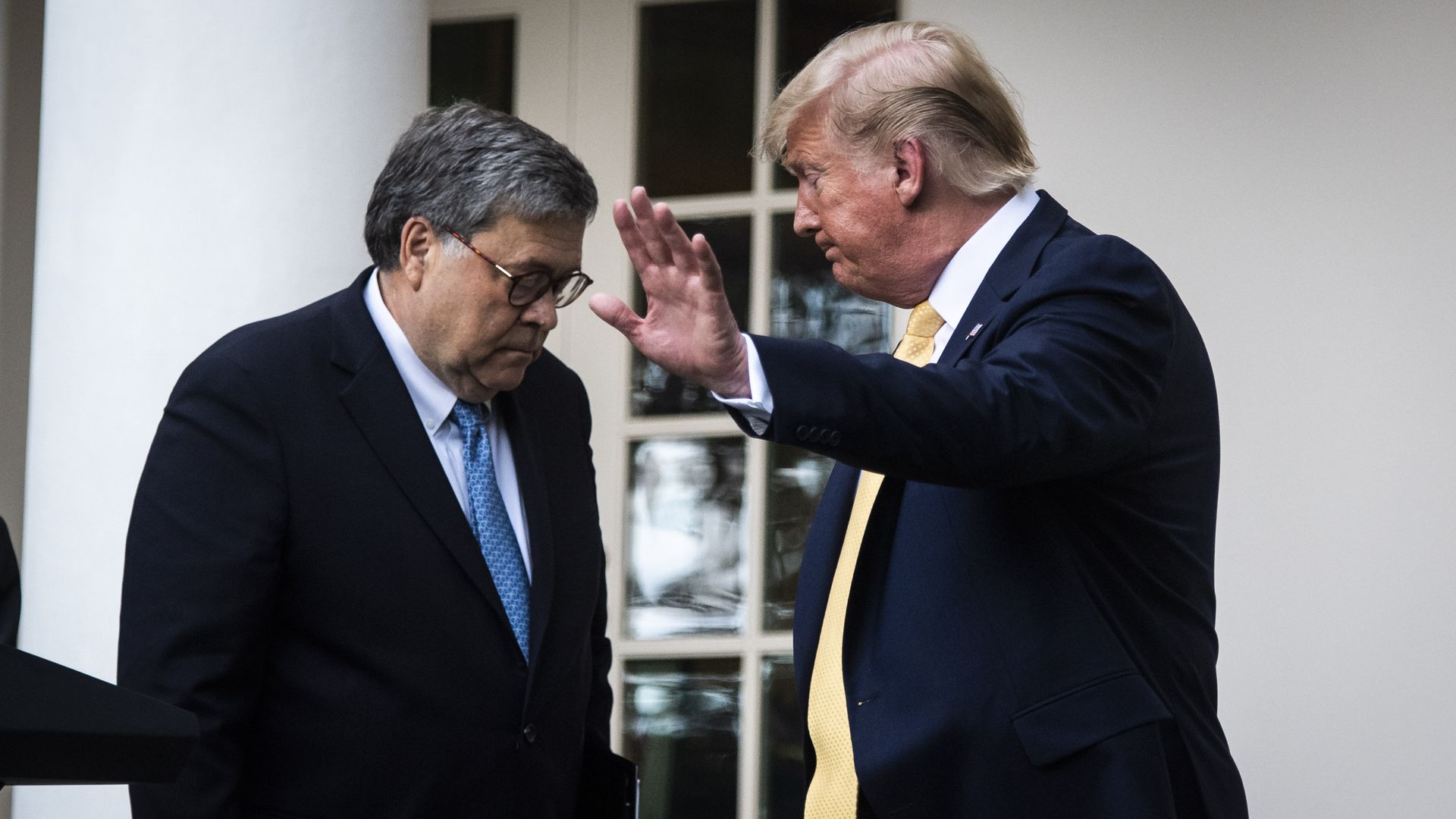 In this image, Trump and Barr stand in front of each other wearing suits in the Rose Garden.
