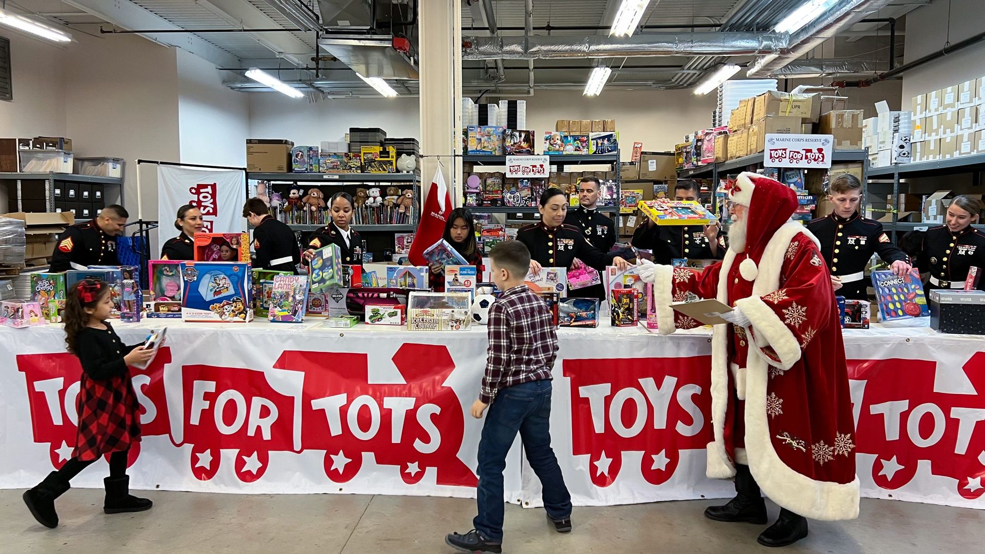 children pick up gifts from marine corp members