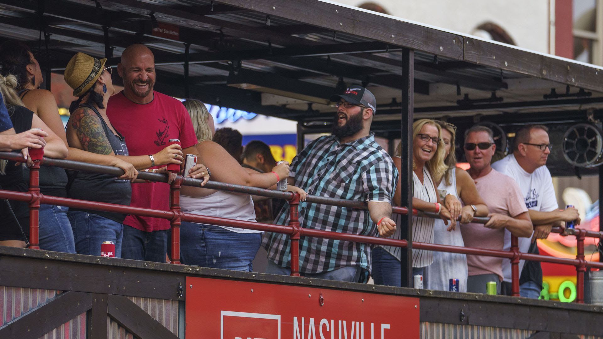 People riding on Nashville Tractor up Broadway with drinks in their hands.