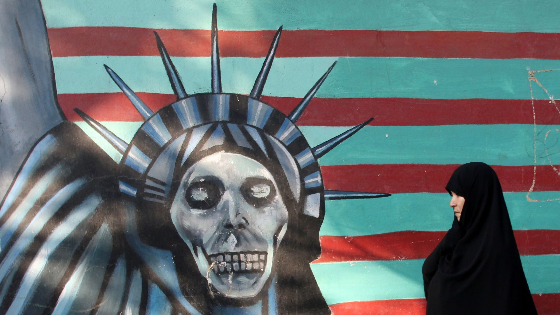 An Iranian woman walks past a mural on the wall of the former US embassy in the Iranian capital Tehran on November 9, 2016. 