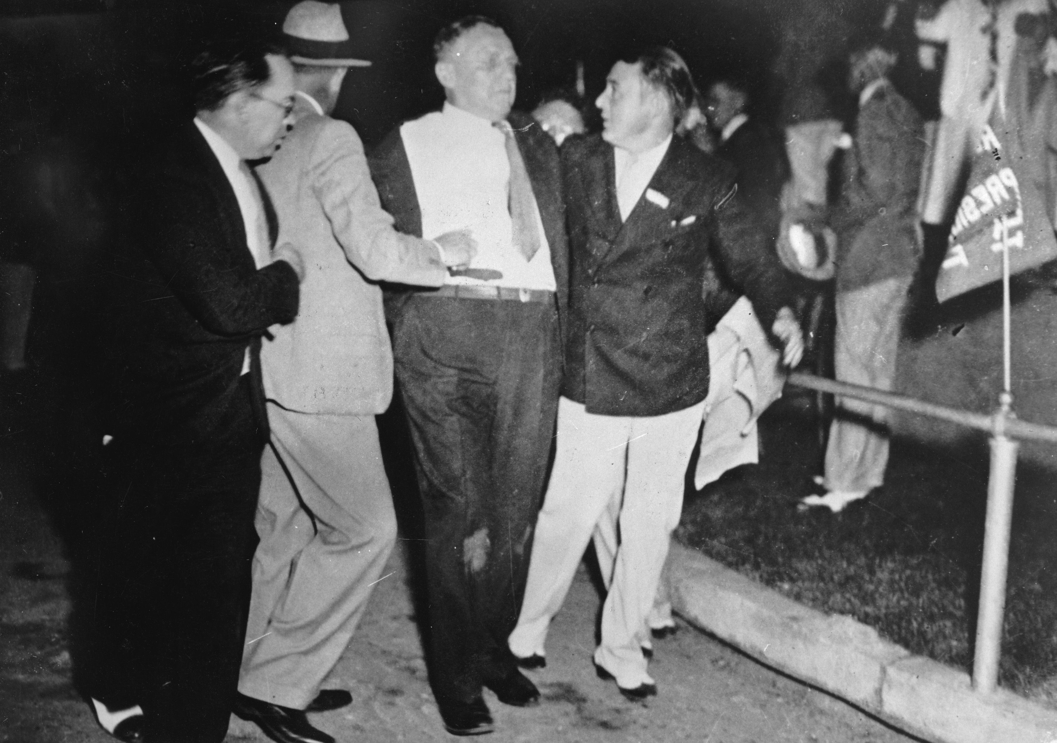 Photo of a man being held up by other men while he was injured 