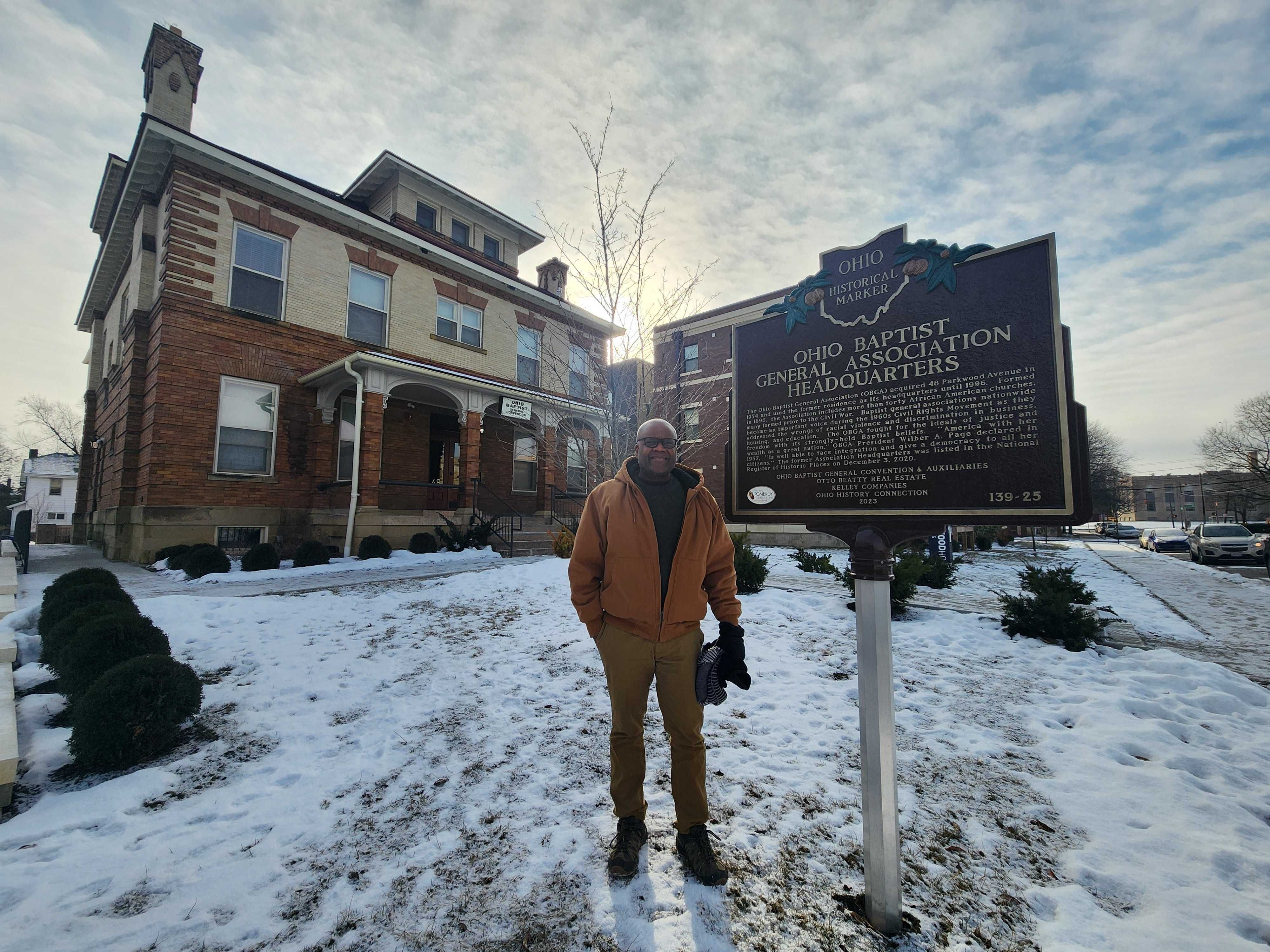 Otto Beatty stands next to a historical marker for the "Ohio Baptist General Association Headquarters."