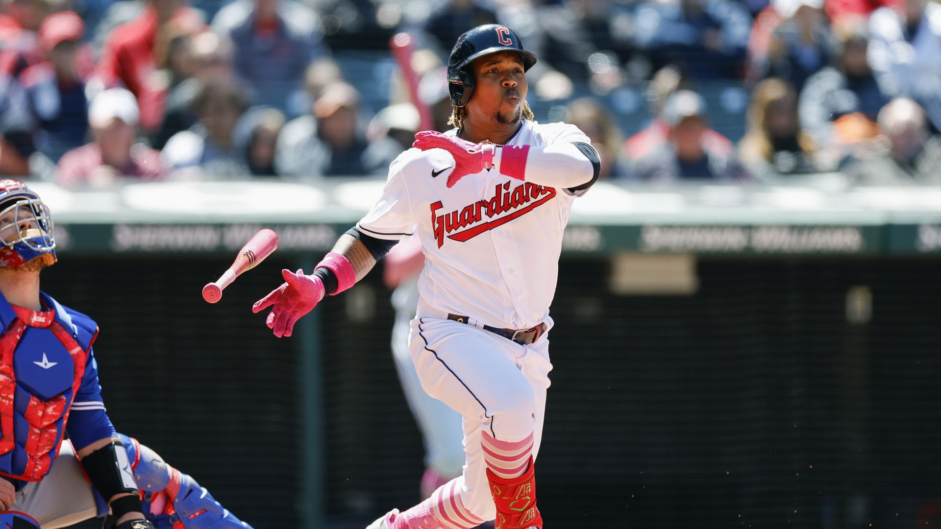 Cleveland Guaridans' Jose Ramirez drops his bat after swinging and hitting the ball into the air as a catcher looks on.