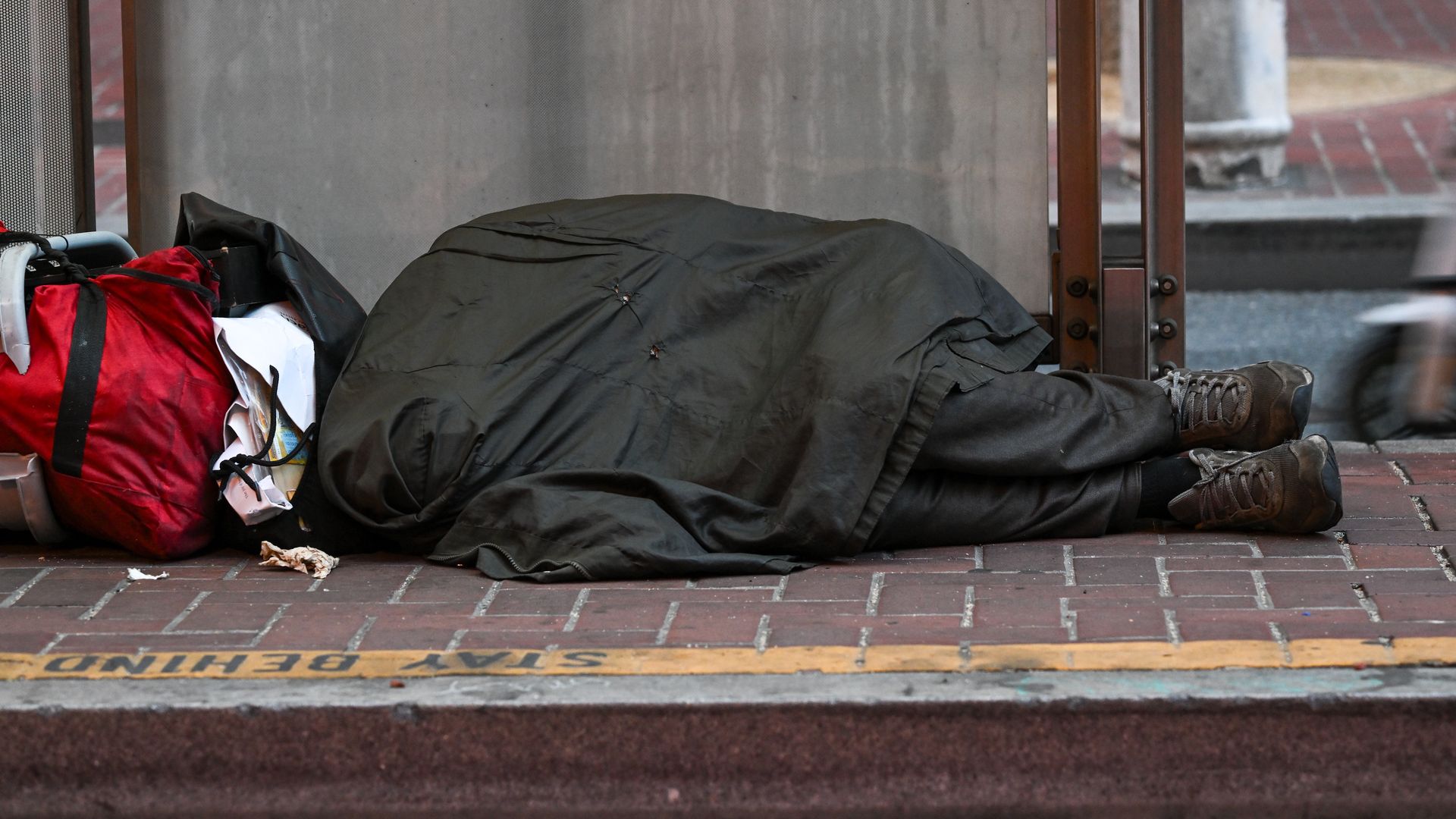 Photo of a homeless person lying on the sidewalk 