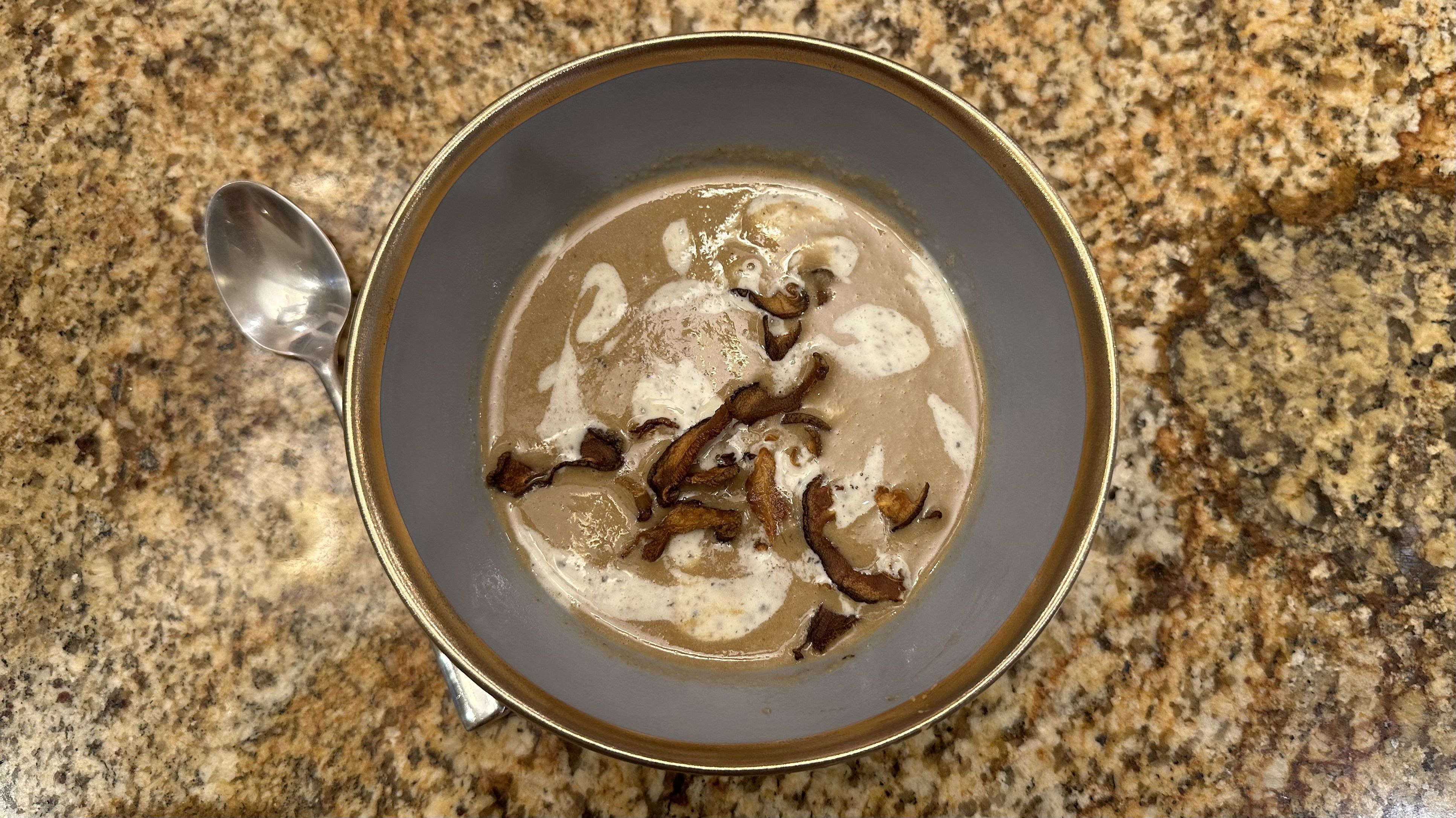 Bowl of velouté soup topped with fried mushrooms and creme fraiche