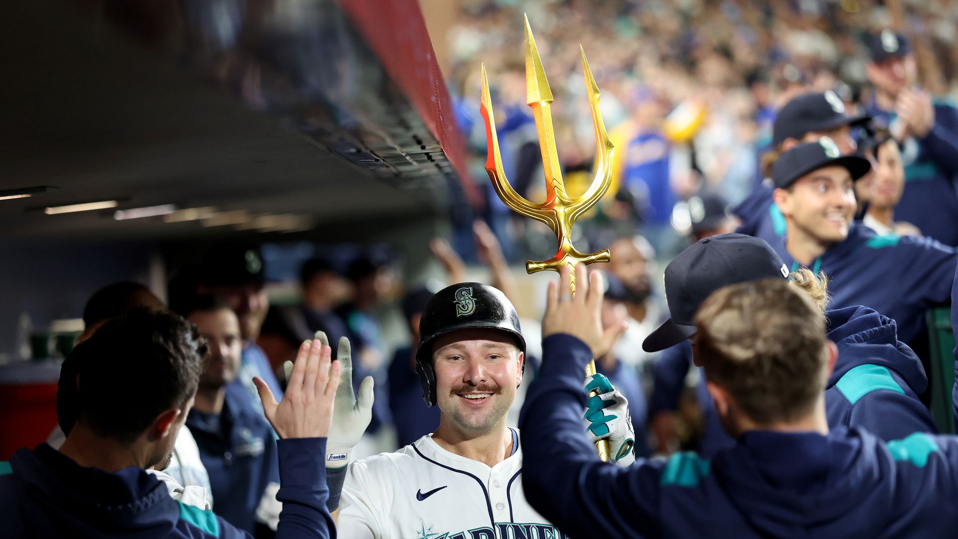 Mariners catcher Cal Raleigh, holding the team's golden trident, is greeted by teammates after belting his 60th homer in a 9-2 win over the Rockies. 