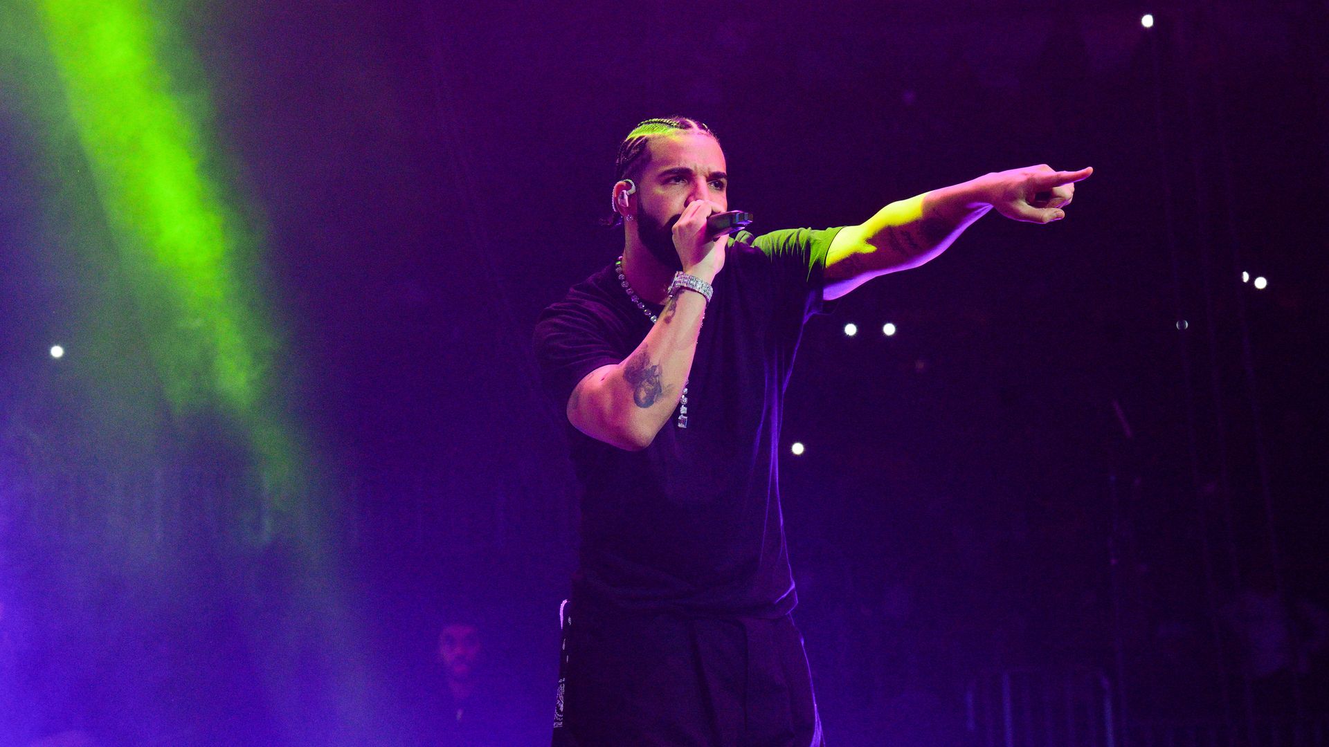 Drake on stage with a microphone pointing out to the crowd.