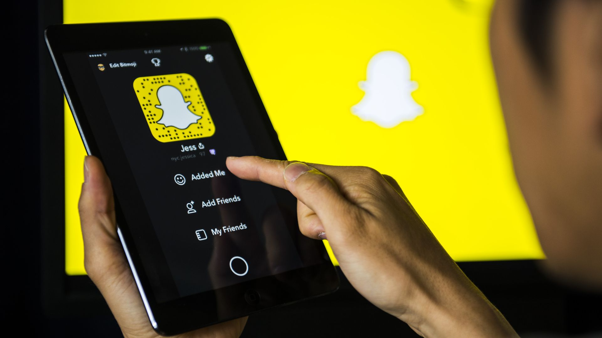 A man holds an Apple iPad Mini as he uses SnapChat app 