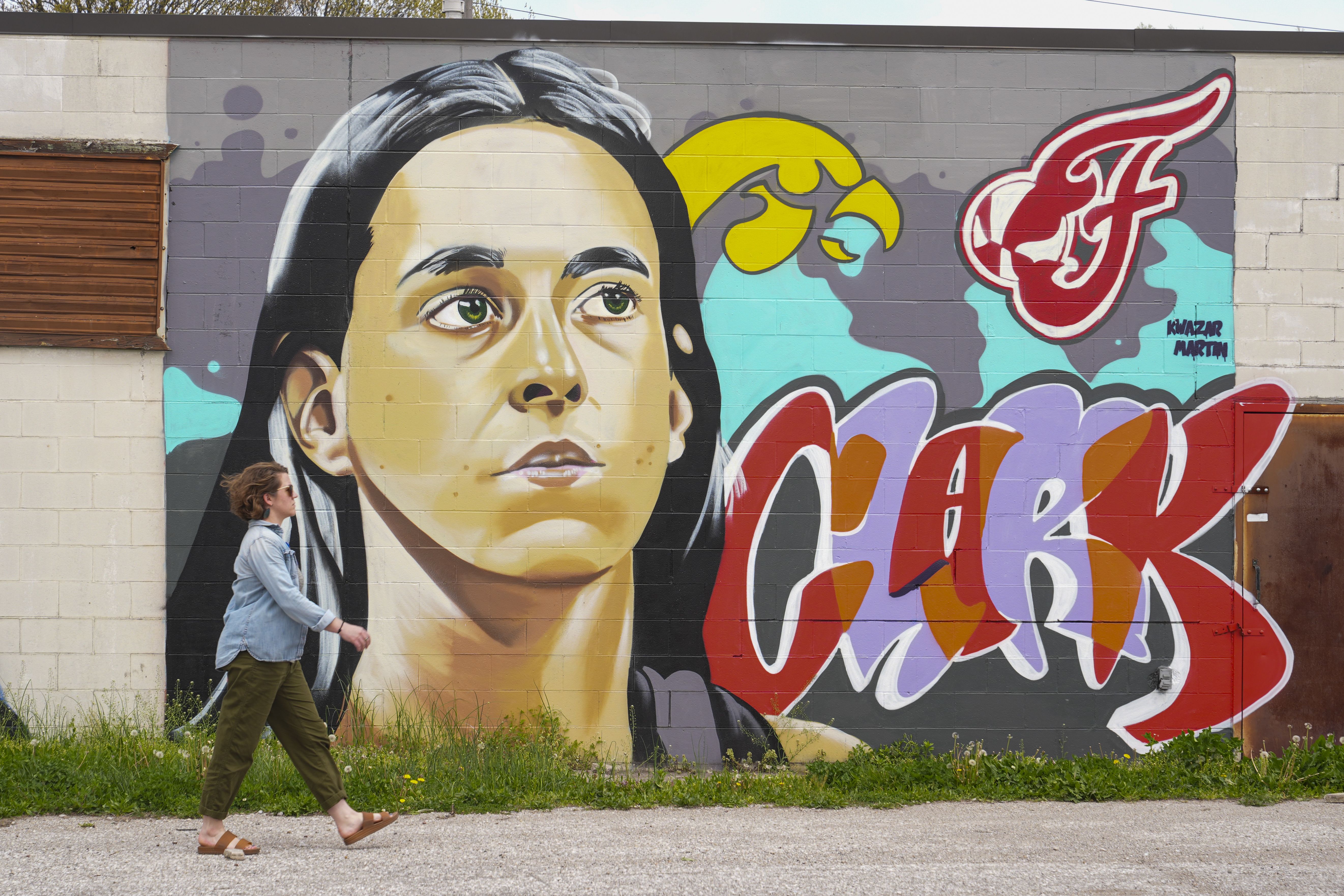 A pedestrian walks past a Caitlin Clark mural in Indianapolis on Tuesday.