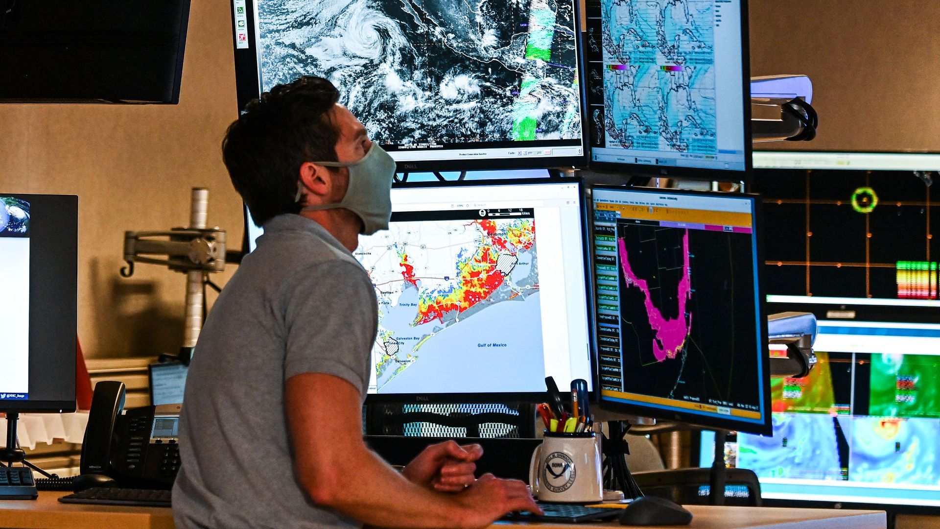 A weather forecaster looks at modeling on screens.