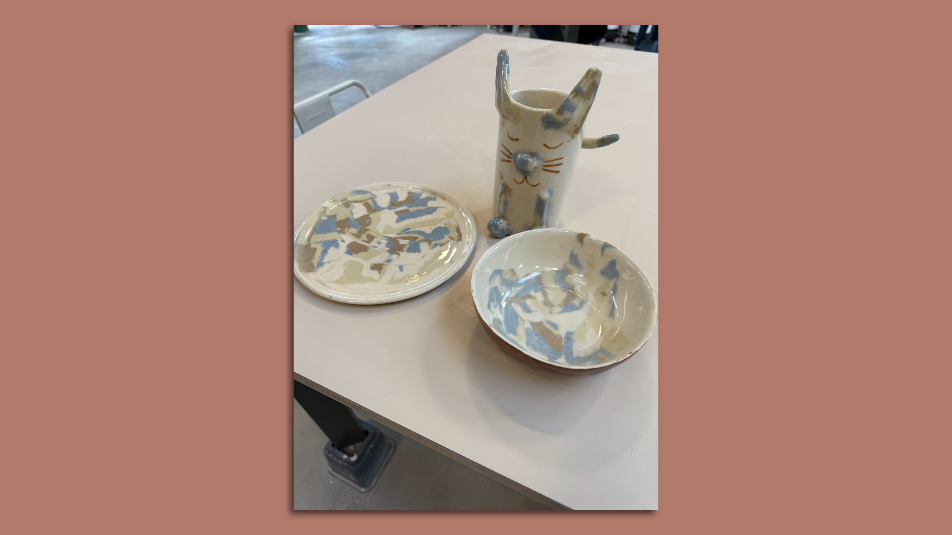Image of a finished, glazed cat vase, plate and bowl with a marbled blue and yellow pattern on them