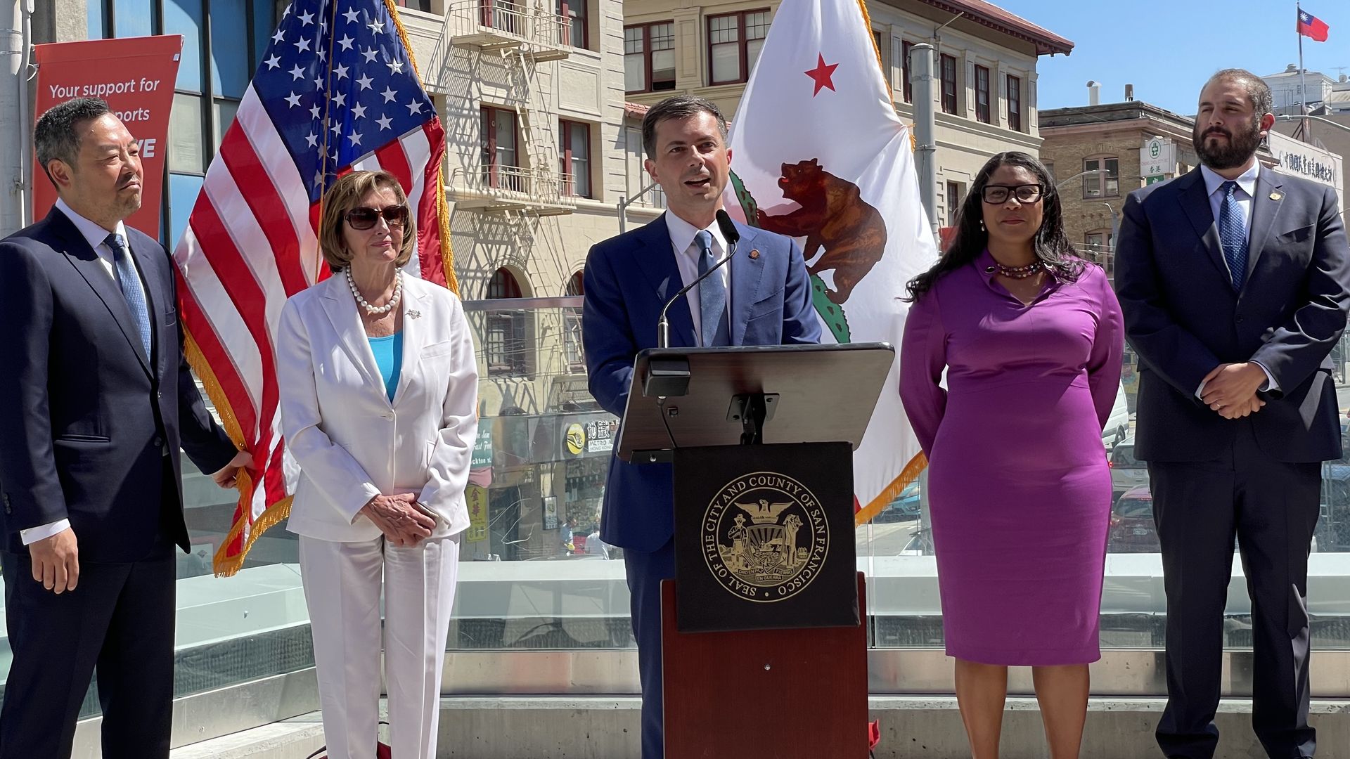 Nancy Pelosi, Pete Buttigieg and London Breed standing in front of U.S. and California state flag