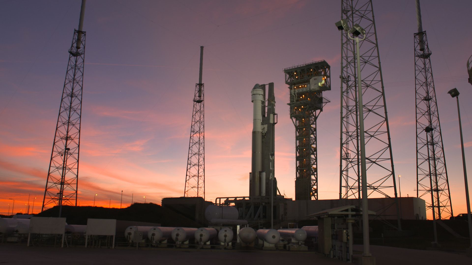 A rocket standing on a pad with a pink sunset behind it in Florida