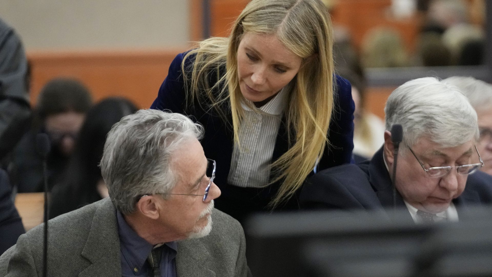 Gwyneth Paltrow leans over a man's shoulder in a courtroom whispering to him "I wish you well"