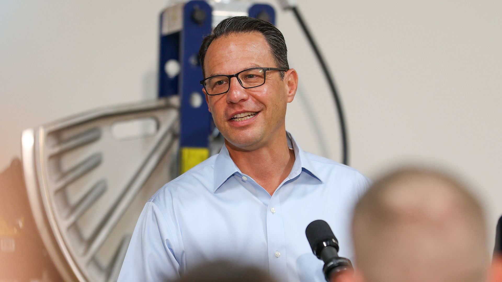 Josh Shapiro smiles as he speaks behind a microphone.