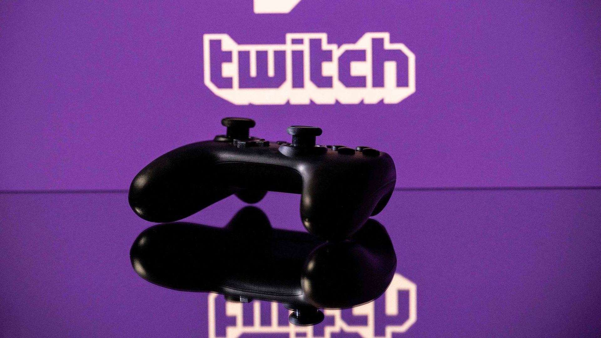 A photo illustration with a modern game controller in the foreground and a Twitch logo in the background.