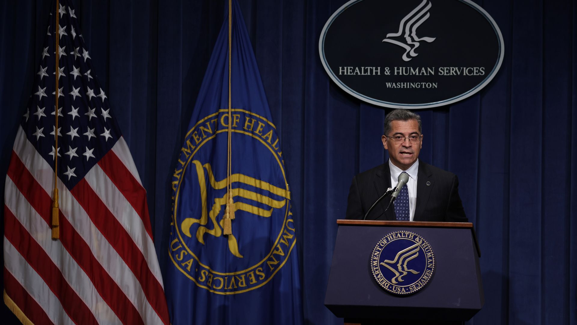 Photo of Xavier Becerra speaking from a podium with the HHS seal behind him