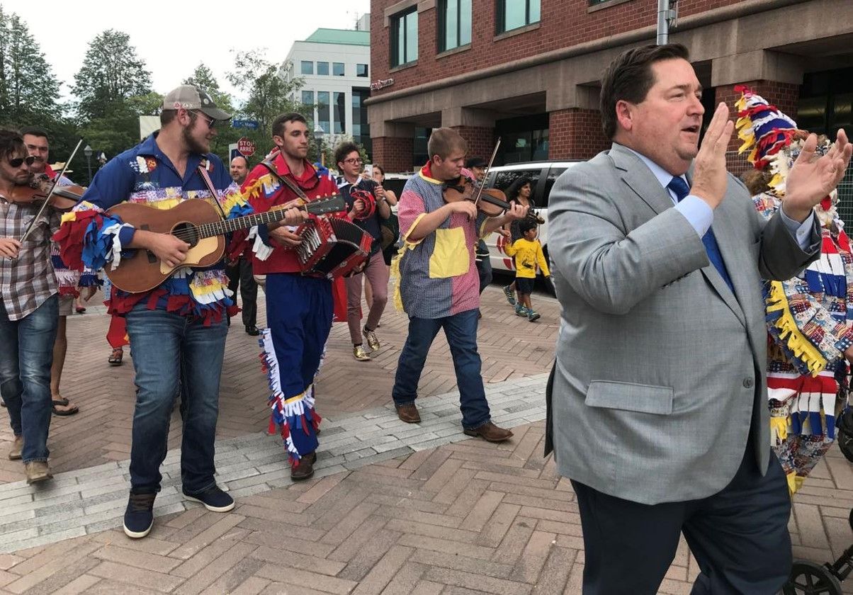 Lt. Gov. Billy Nungesser claps as he walks at the front of a parade of musicians dressed for Cajun Mardi Gras.
