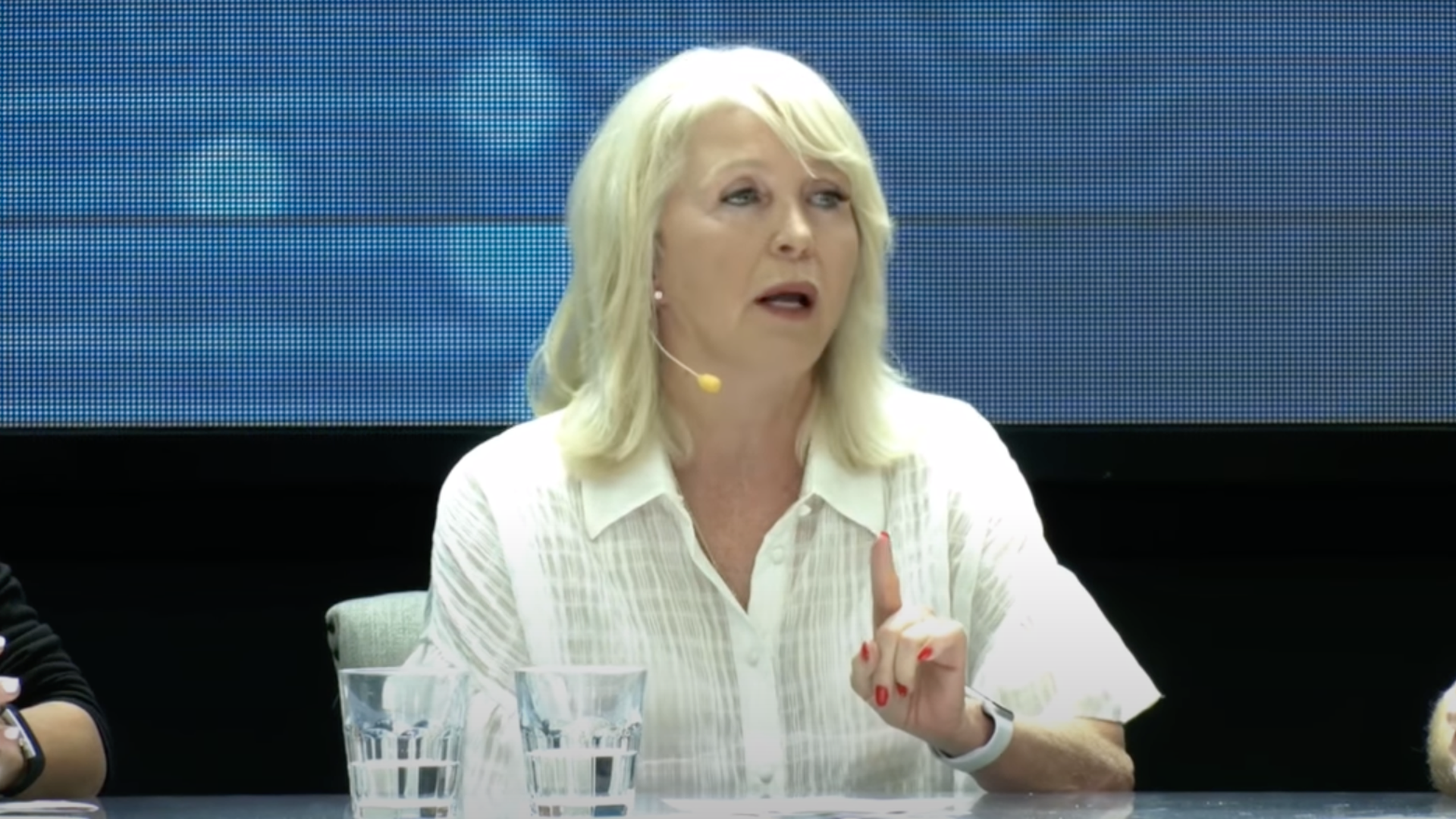 A photo of Tina Peters with her hand and index finger raised.