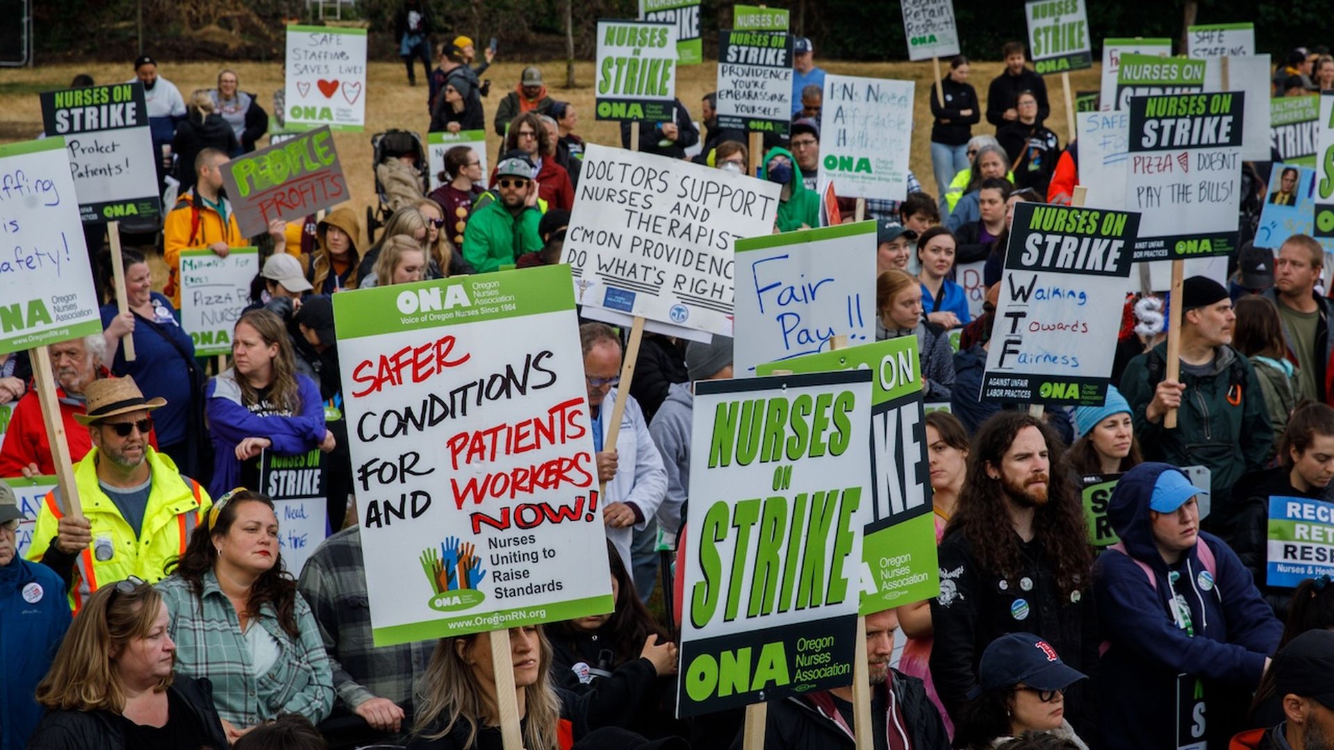 A photo of a group of two dozen-plus people holding signs in support of a nurses' strike.