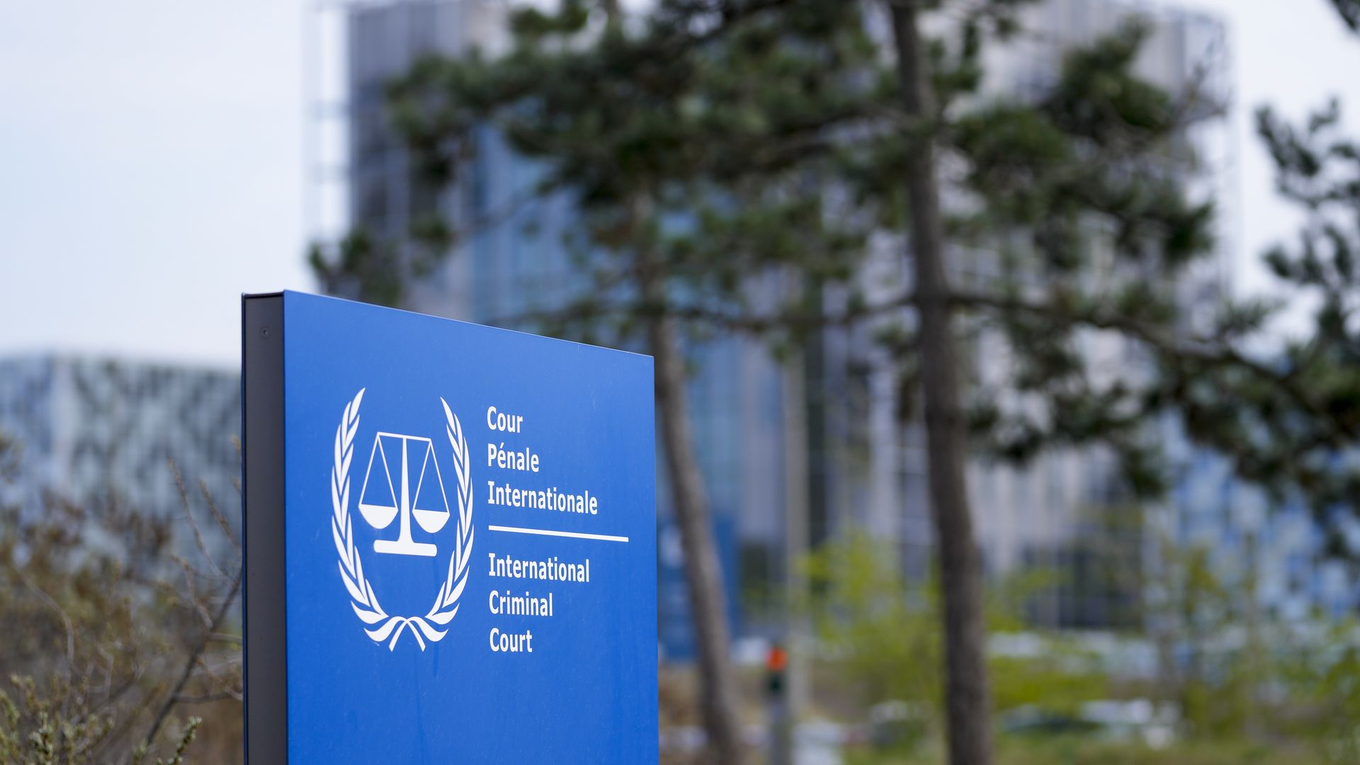 Blue International Criminal Court sign in front of trees.