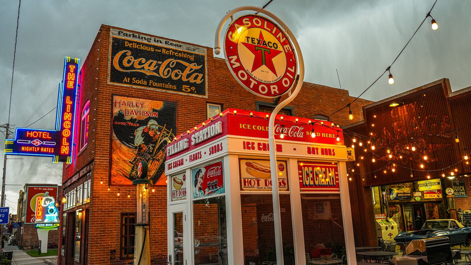 Neon signs advertise The Lincoln Hotel, Texaco gas and the City Garage on buildings on a old-timey Main Street